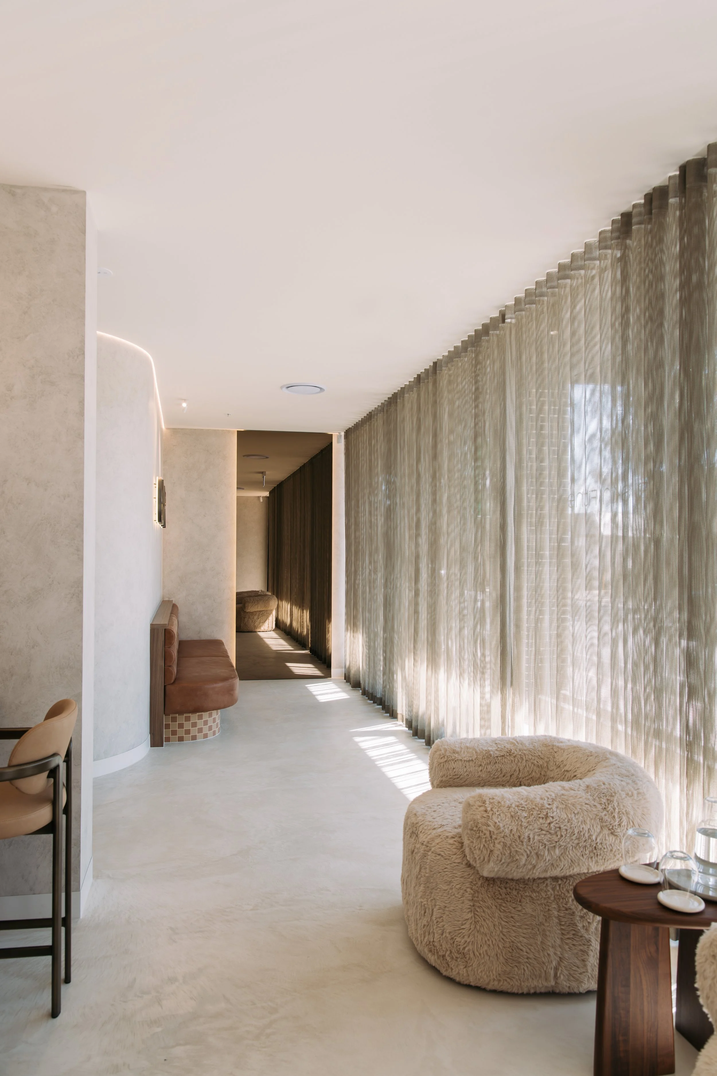 Elixir Skin Fitness waiting area with sheer curtains and rounded upholstered seating
