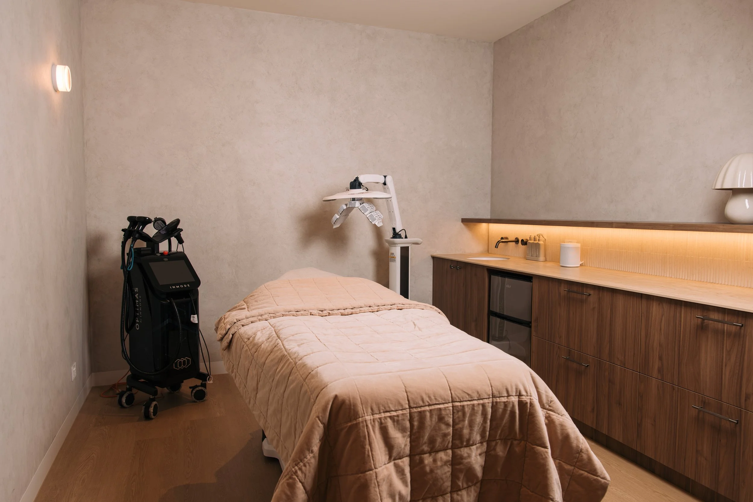 Treatment bed beside timber cabinetry in an Elixir Skin Fitness treatment room