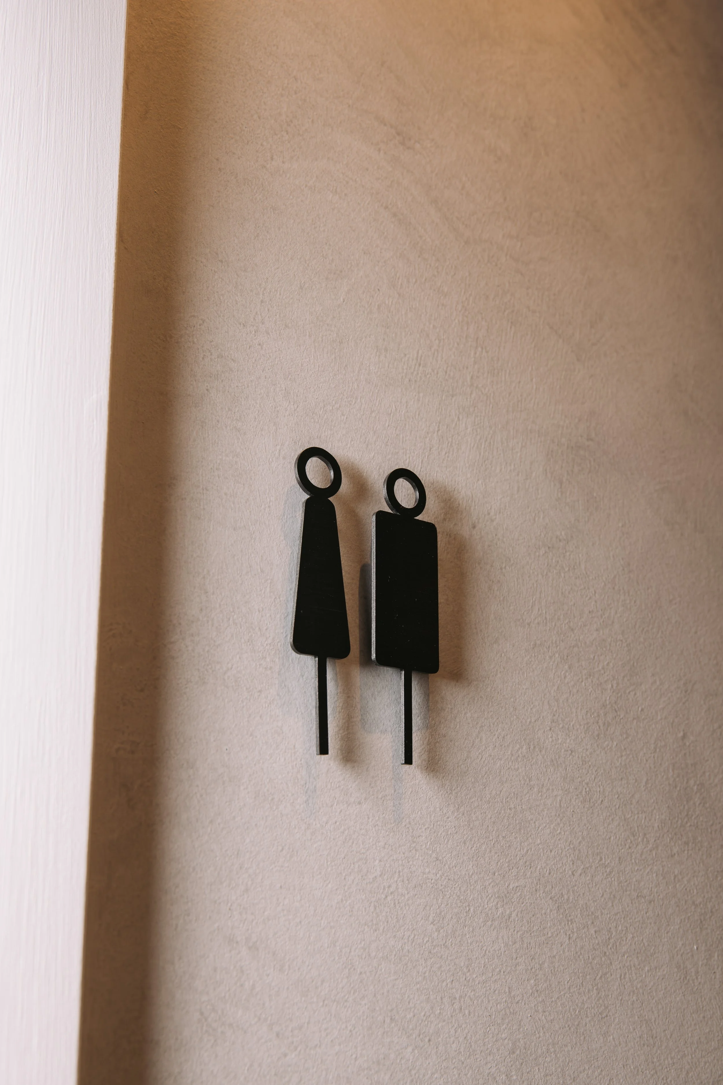 Dark wall hooks against a textured wall at Elixir Skin Fitness