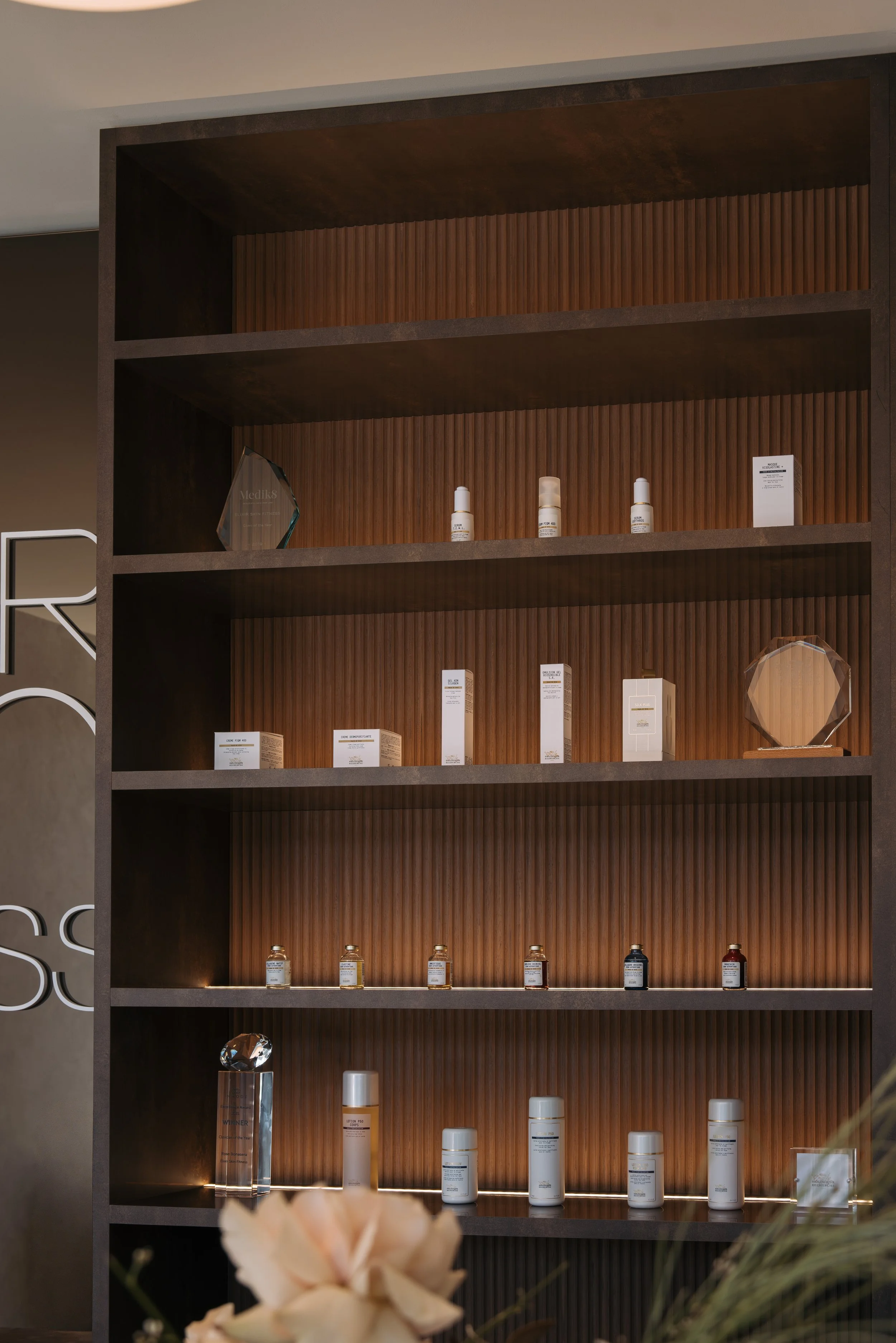 Skincare products displayed on dark timber shelves at Elixir Skin Fitness