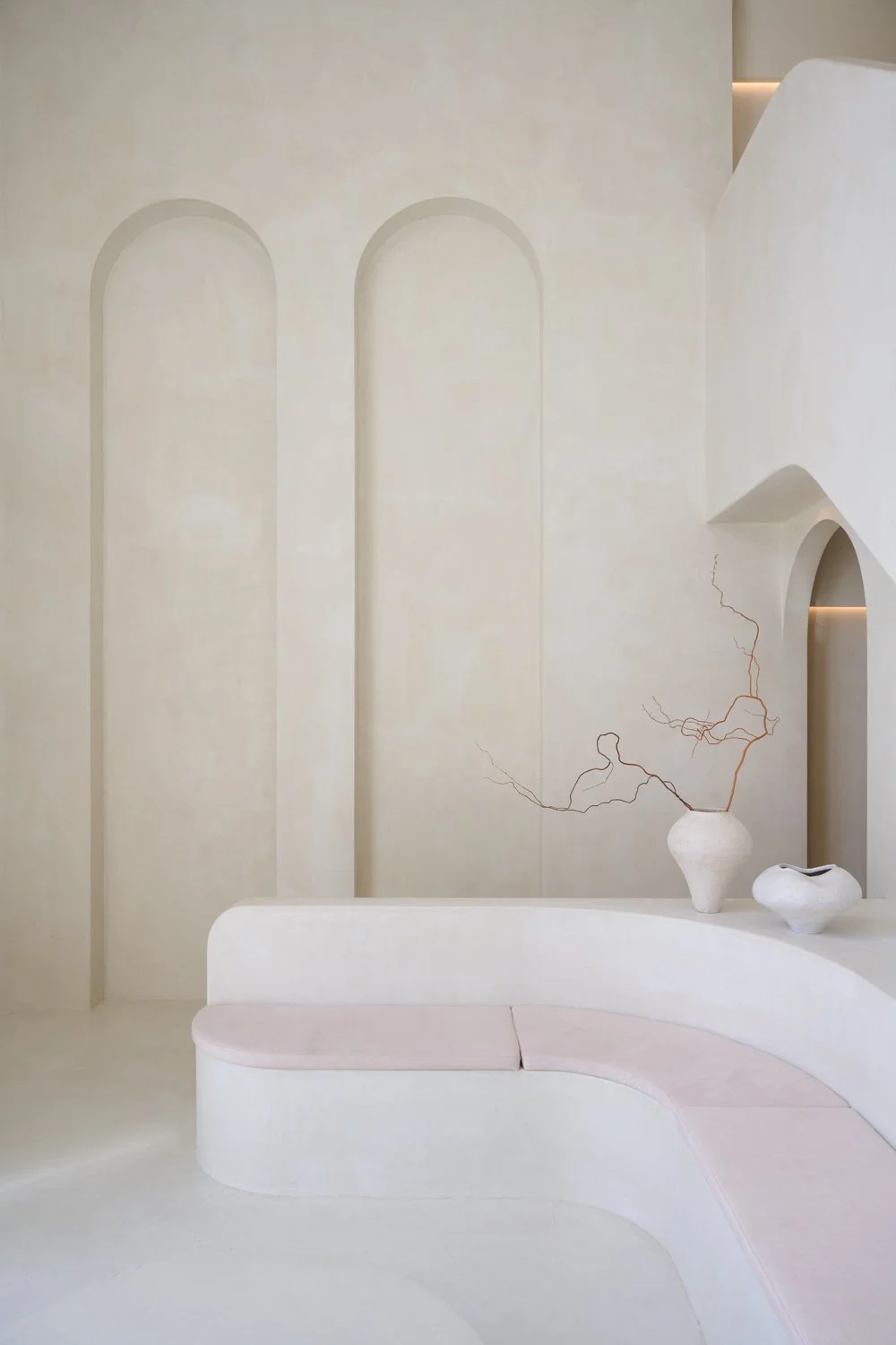 Pale plaster reception desk, wall niches and ceramic décor at Sculpt Skin Clinic