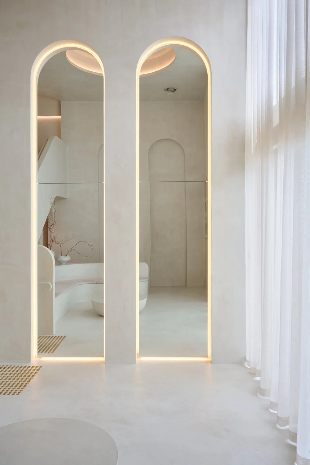 Tall arched mirrors beside sheer curtains at Sculpt Skin Clinic