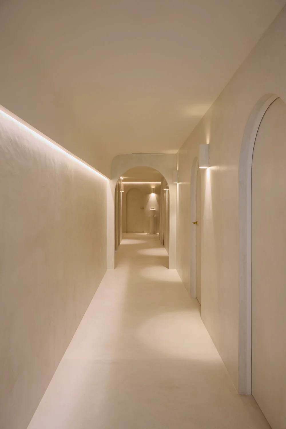Long curved corridor with warm linear lighting at Sculpt Skin Clinic