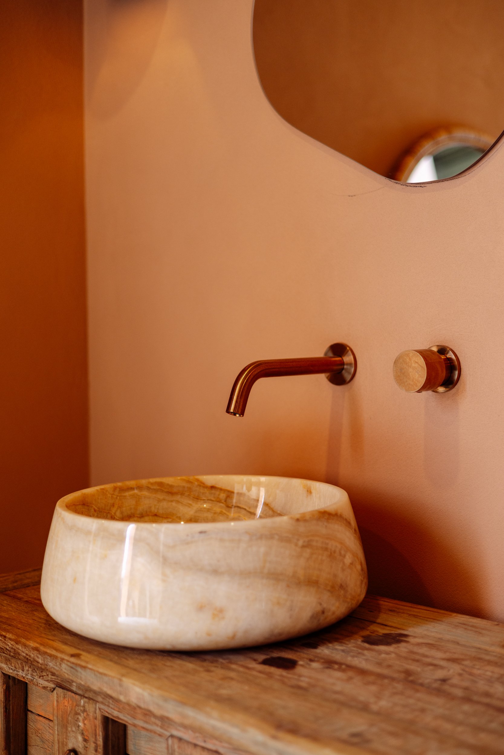 Natural stone vessel basin with aged-brass wall taps at Stepney Warehouse