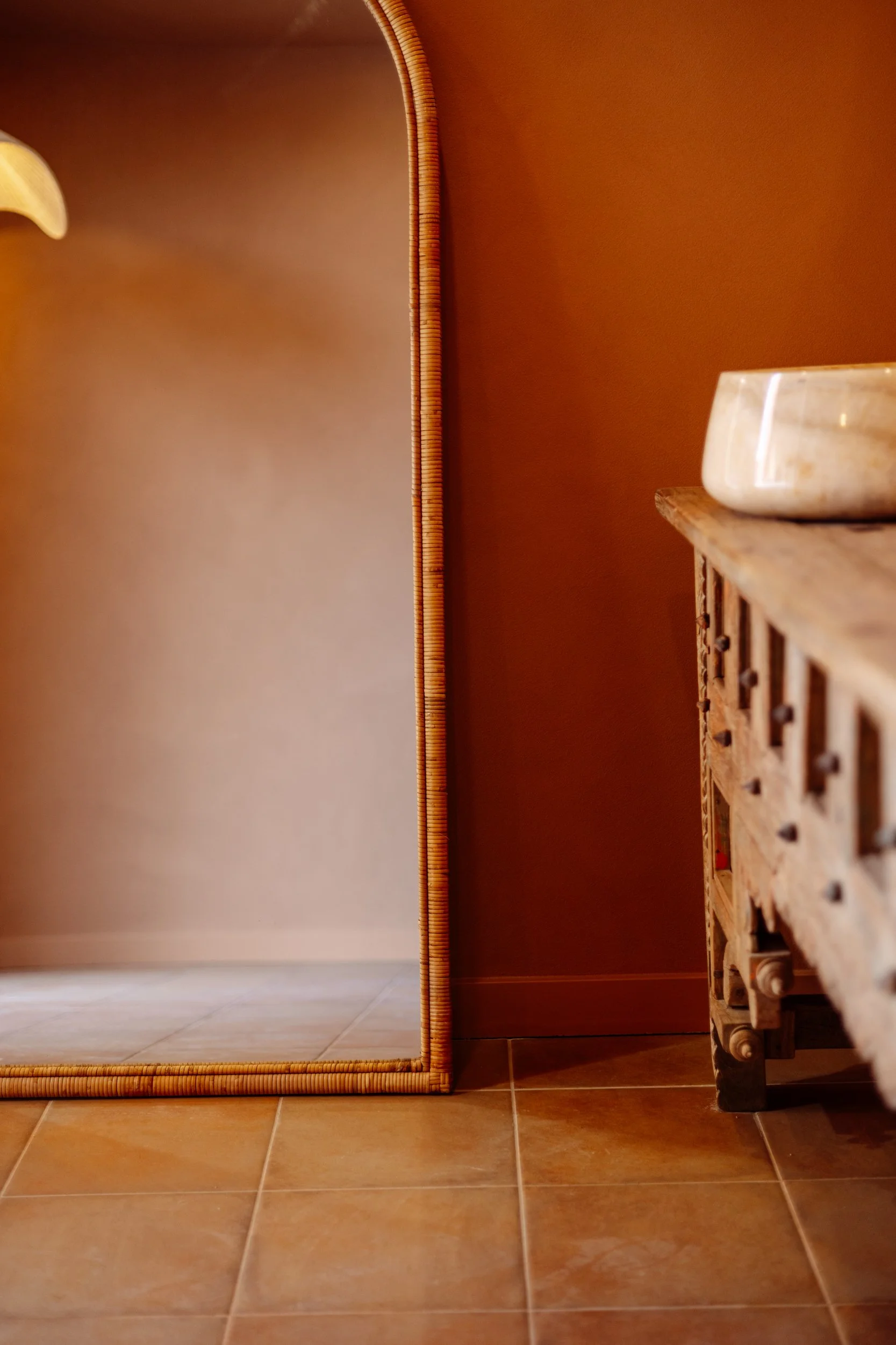 Carved timber vanity beside a terracotta wall and tiled floor at Stepney Warehouse