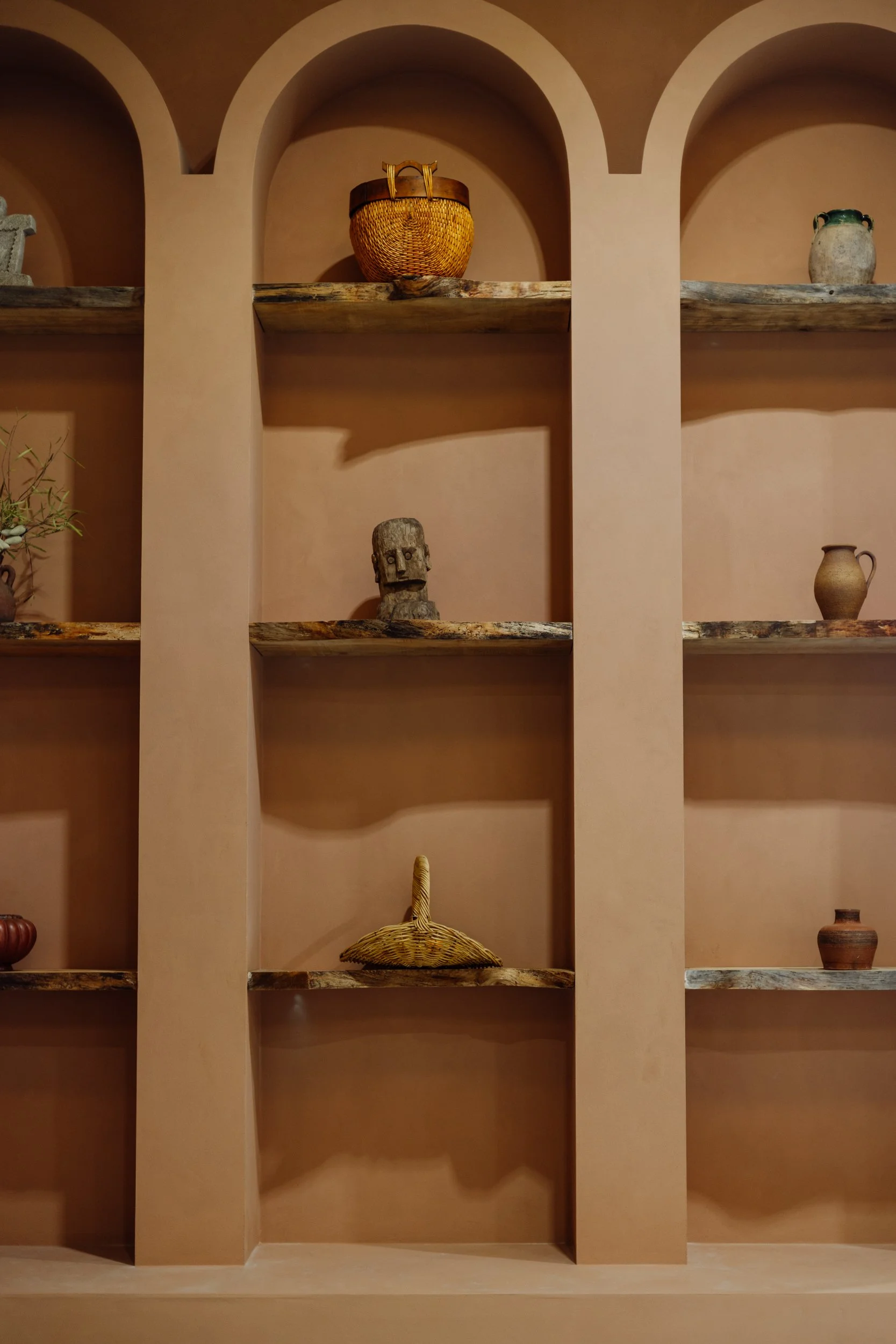 Ceramic objects displayed on built-in terracotta shelves at Stepney Warehouse
