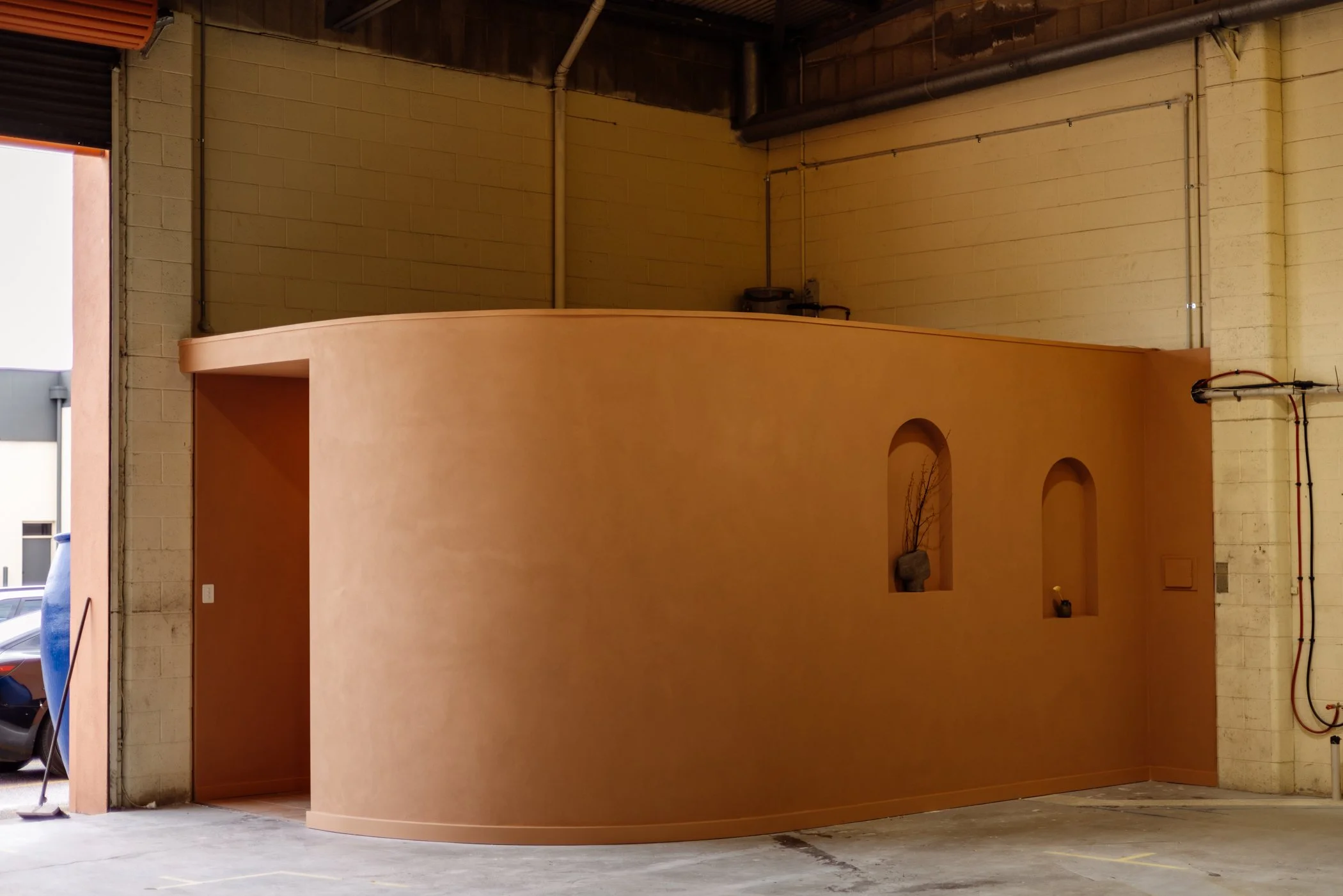 Terracotta-rendered internal structure beneath the industrial warehouse roof in Stepney