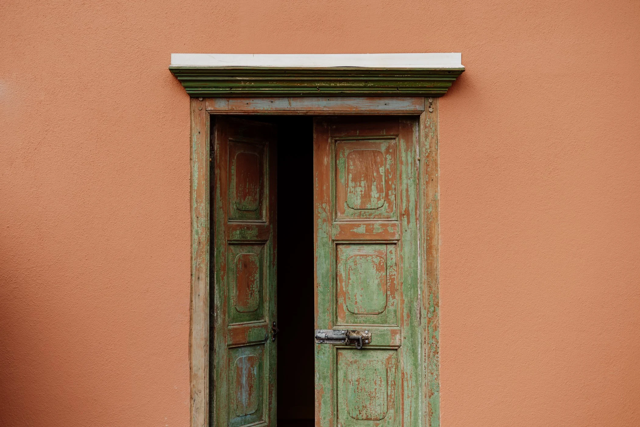 Weathered green timber doors set into a terracotta wall at Stepney Warehouse