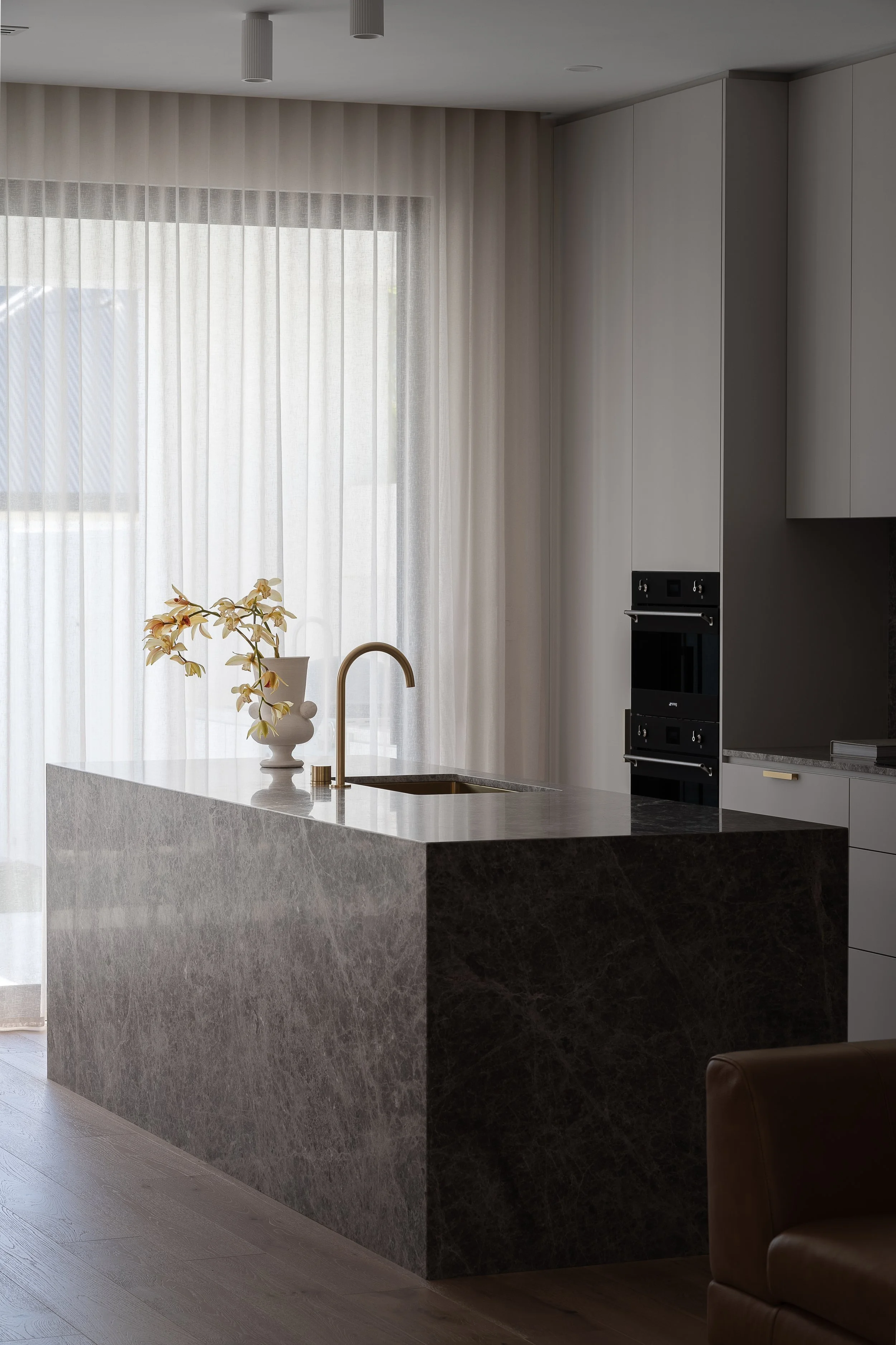 Glynde kitchen with pale cabinetry, a stone island and full-height sheer curtains