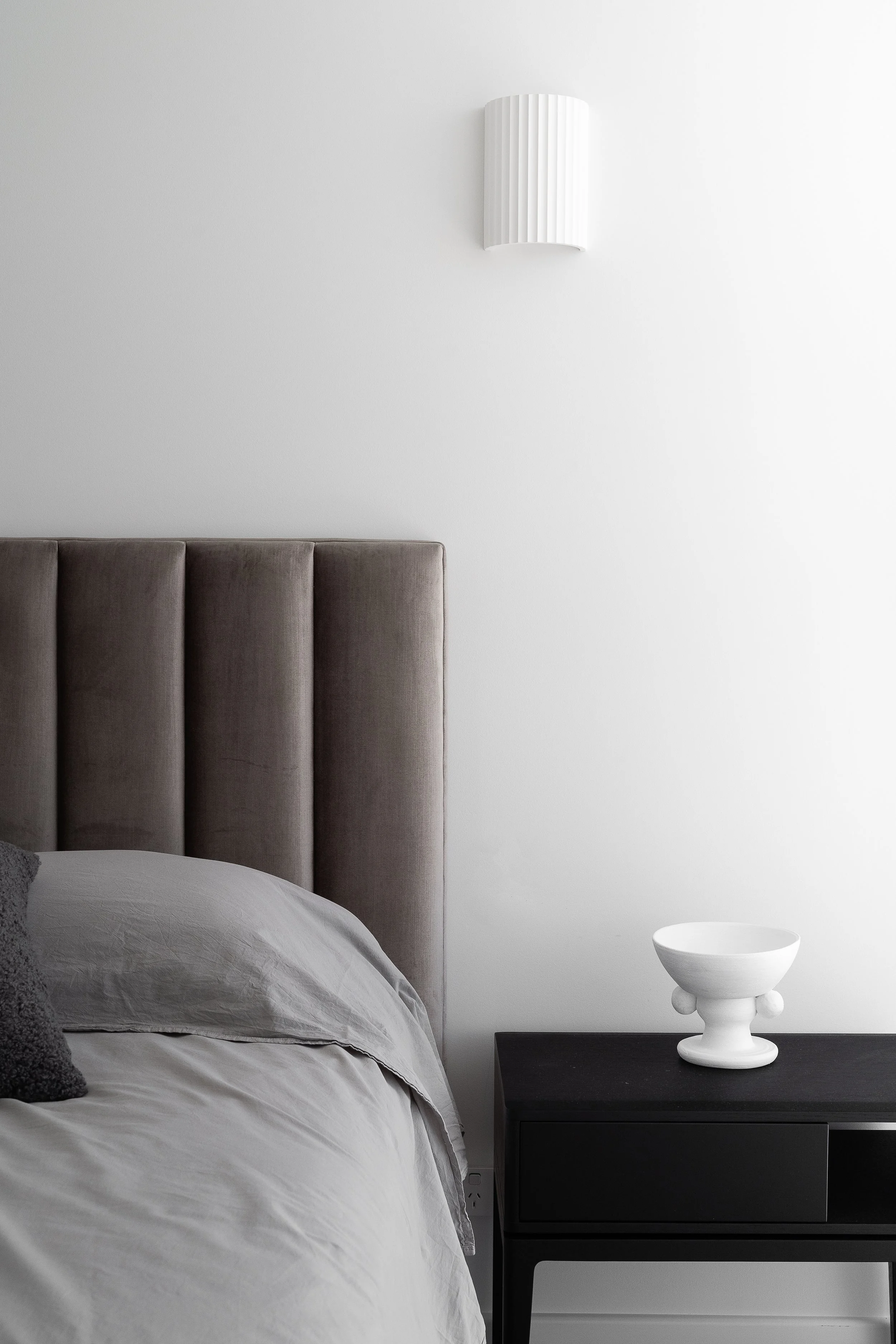 Upholstered bedroom headboard and bedside table in the Glynde home