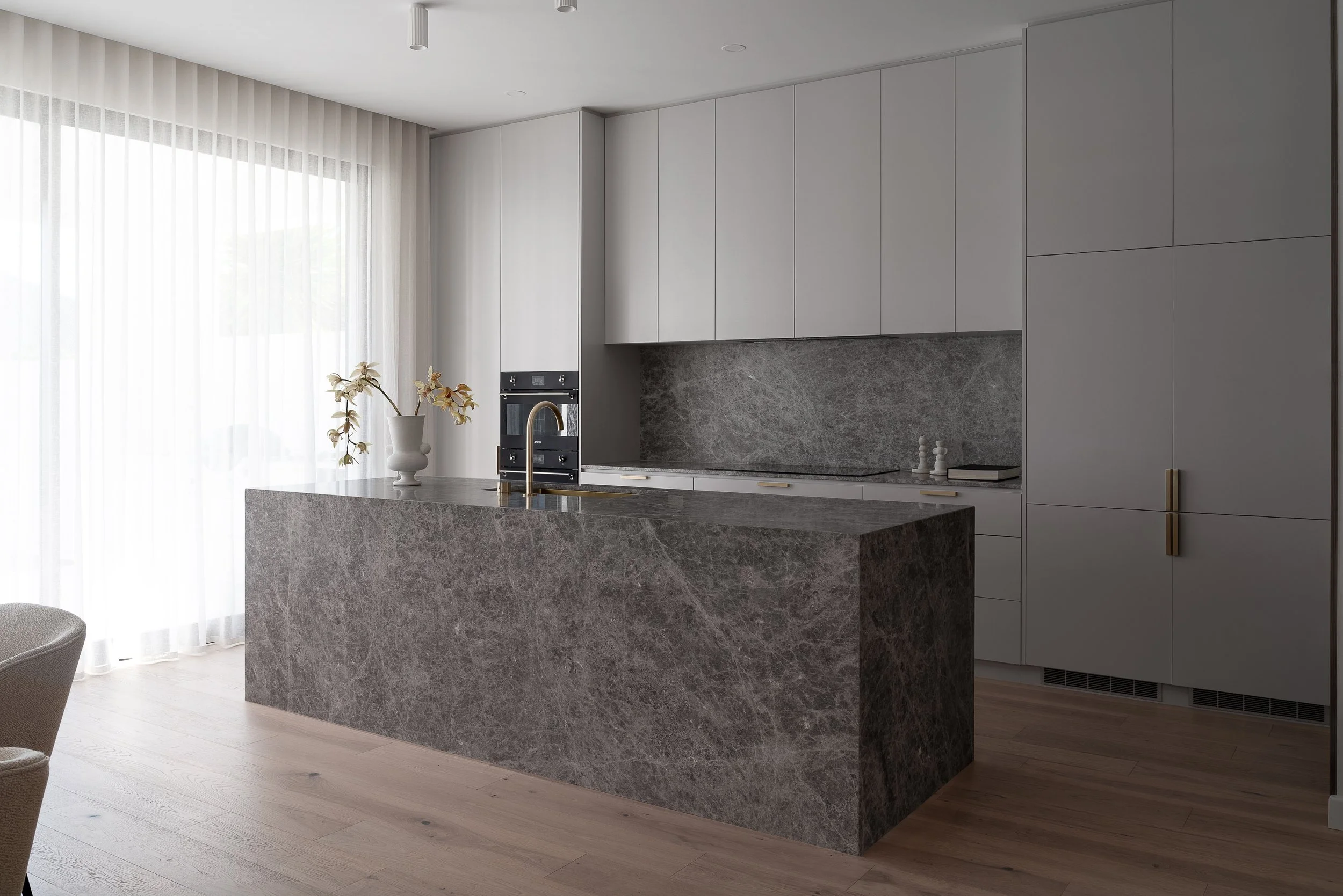 Stone kitchen island beneath pale cabinetry in the Glynde home