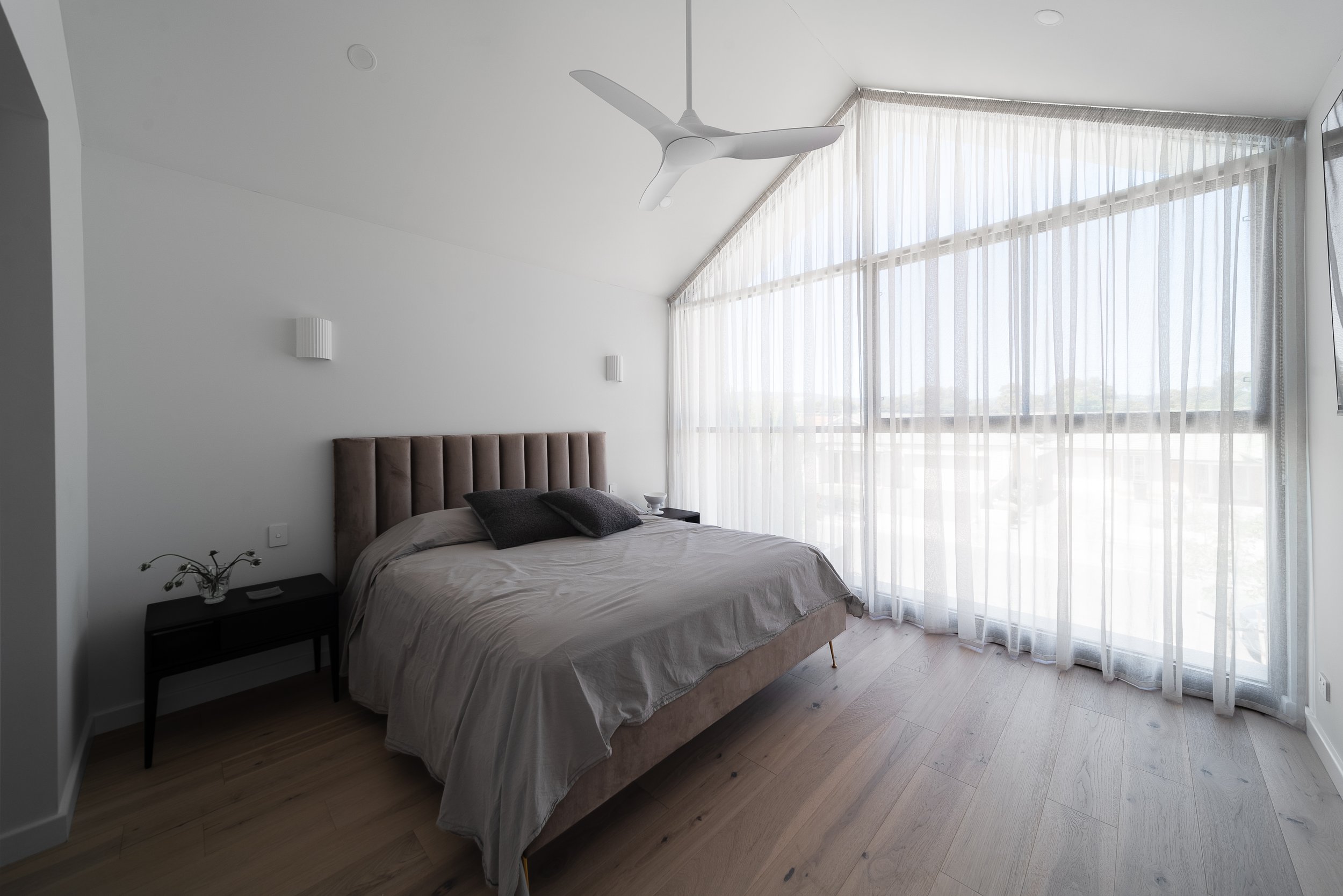 Glynde bedroom with an upholstered headboard and full-height sheer curtains