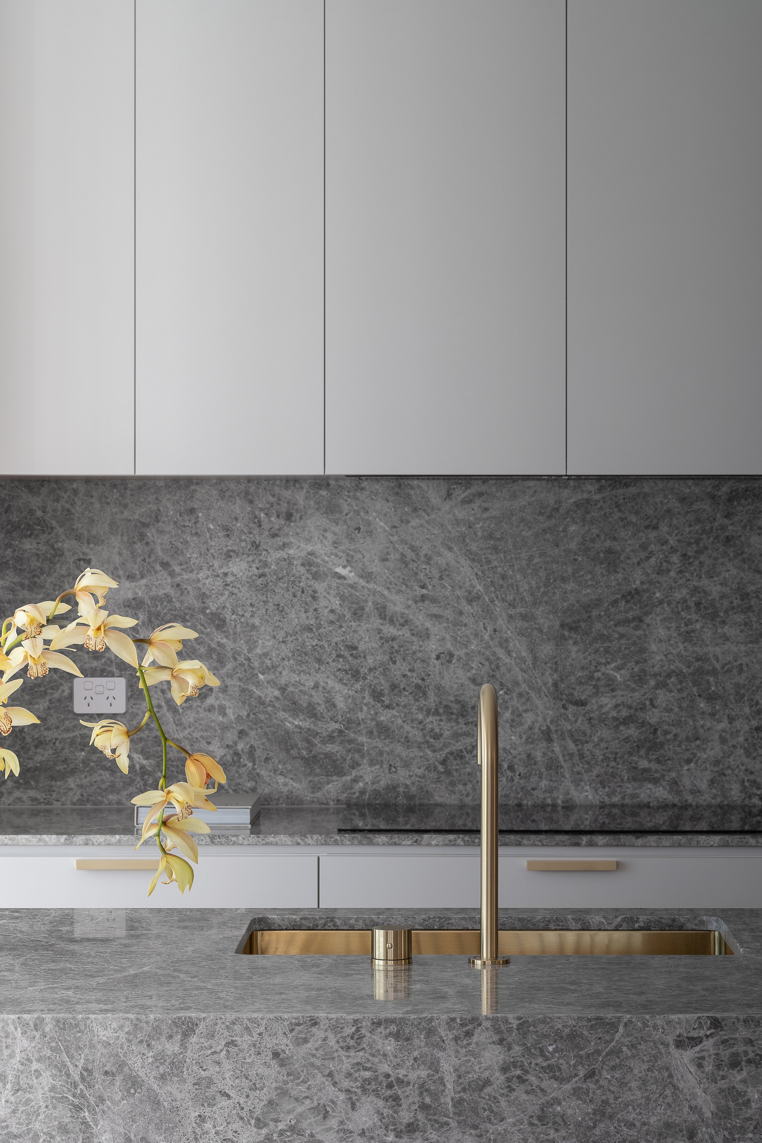 Brass kitchen tap and veined stone splashback in Glynde