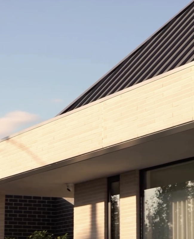 Contemporary Adelaide home exterior with pale brickwork, dark roof cladding and large windows