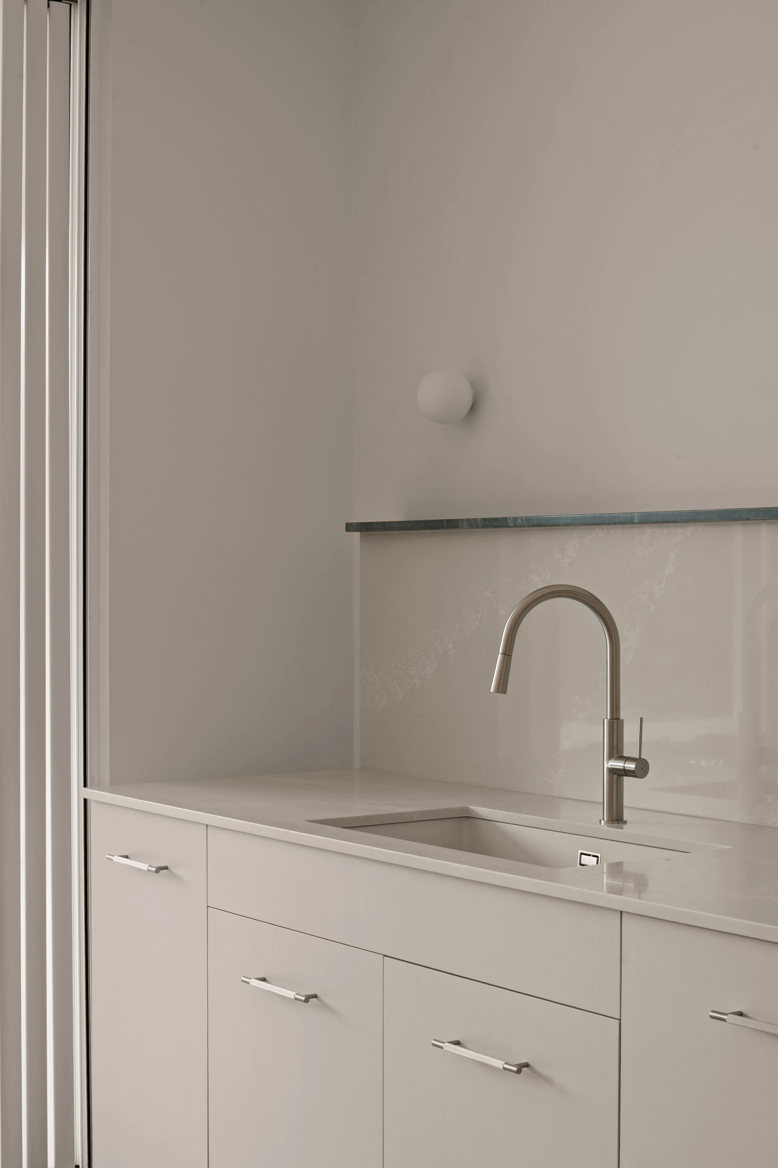 Kitchen sink and wall-mounted tap beneath pale cabinetry in Glenelg North