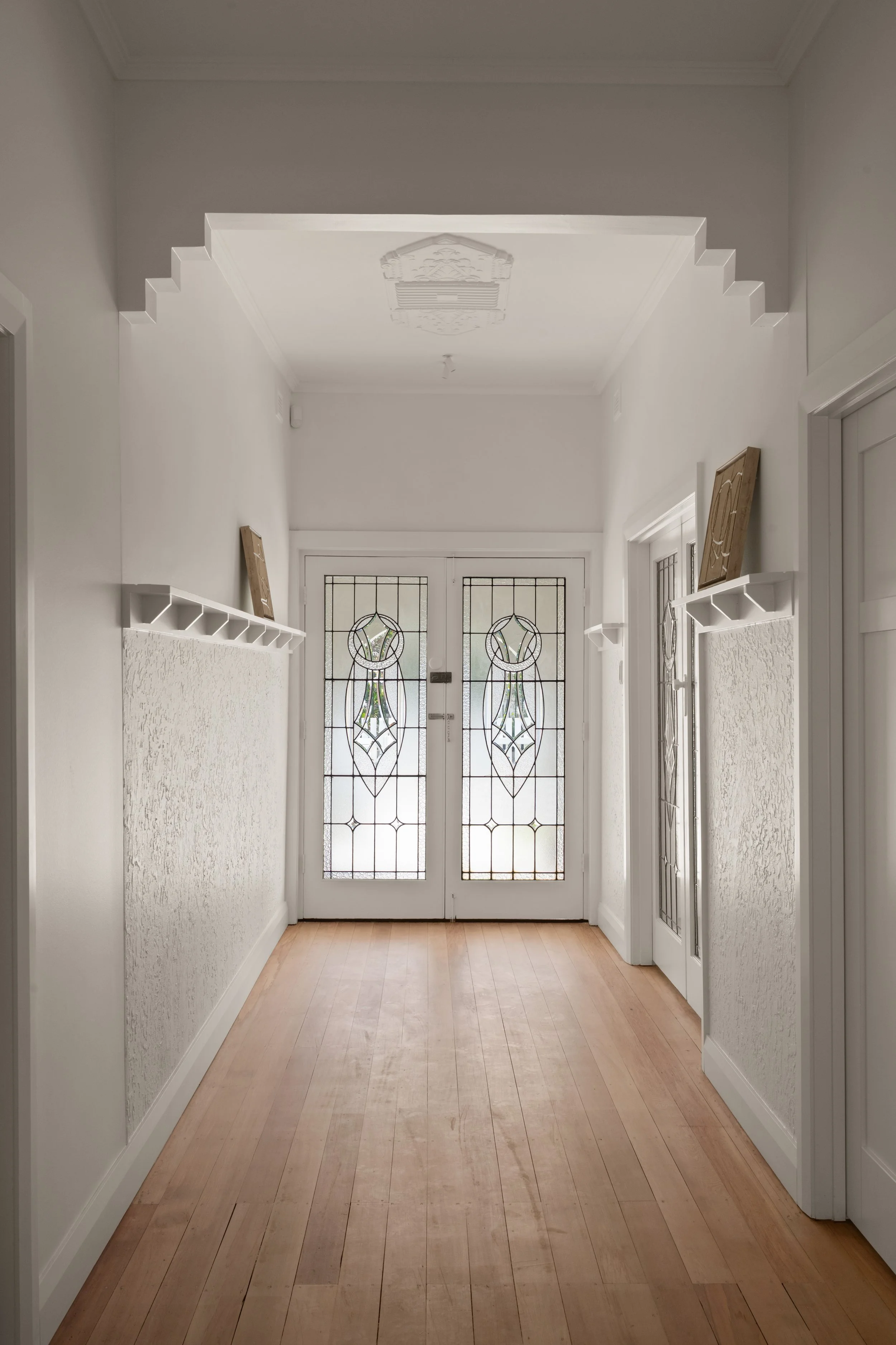Light-filled hallway with timber flooring and leadlight doors in Glenelg North