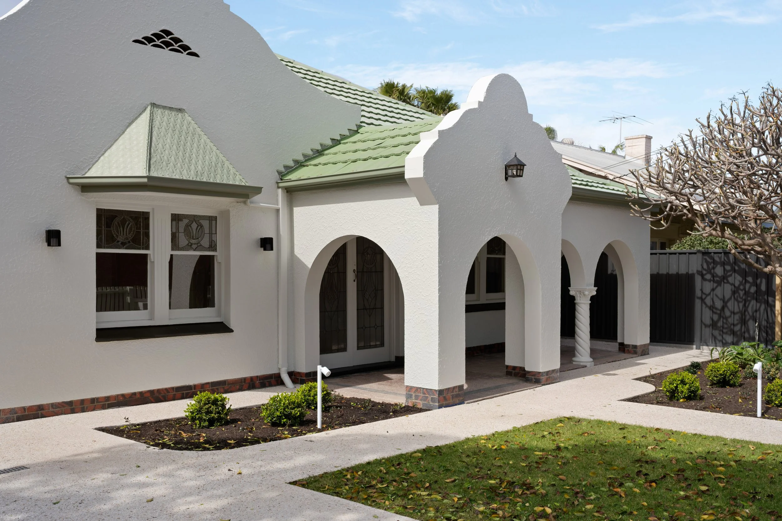 Art Deco façade with white render and a green tiled roof in Glenelg North