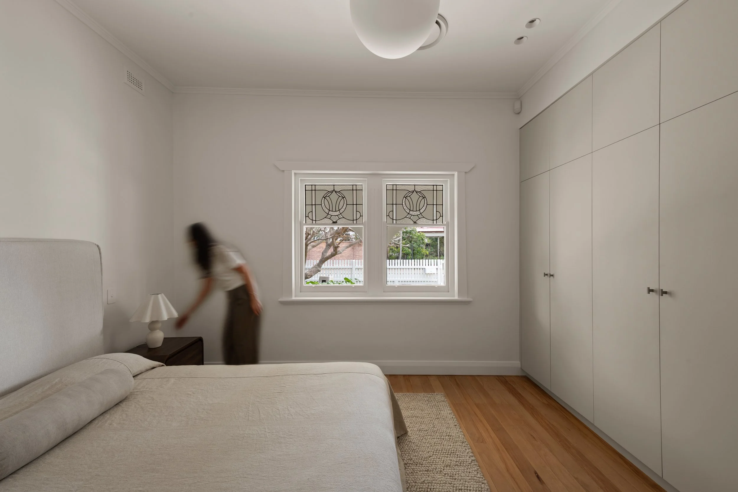 White bedroom with timber flooring and decorative leadlight windows in Glenelg North
