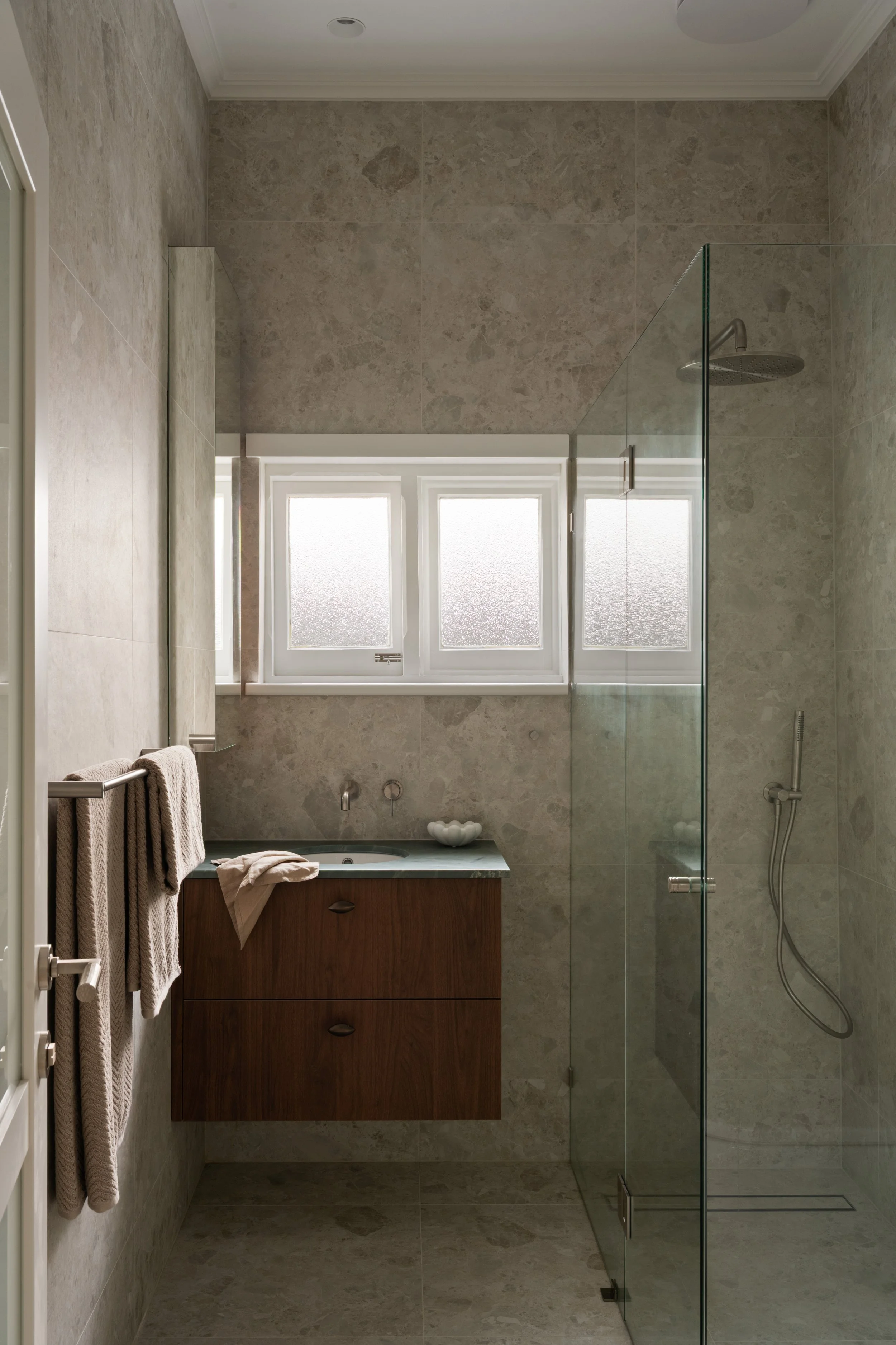 Green stone vanity benchtop beneath bathroom windows in Glenelg North