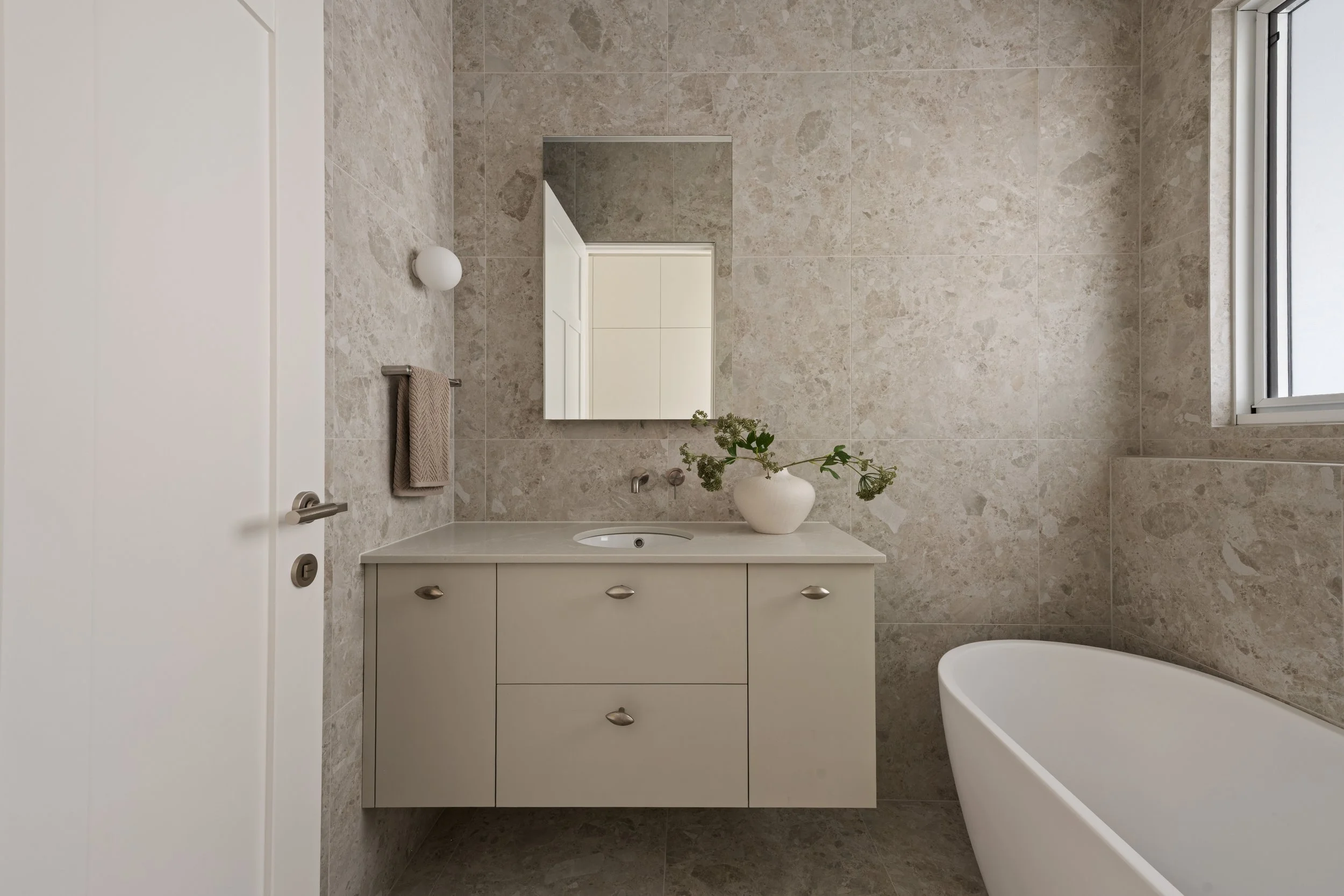 White bathroom vanity, tiled walls and bathtub in the Glenelg North home