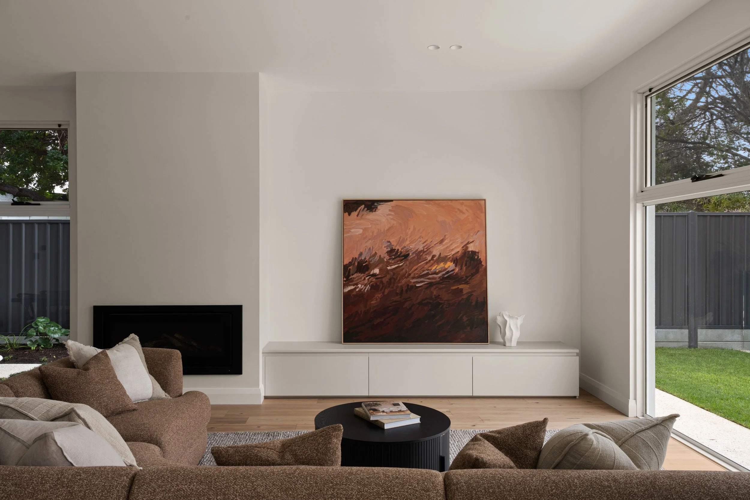 Glenelg North living room with a fireplace, artwork and curved sofa