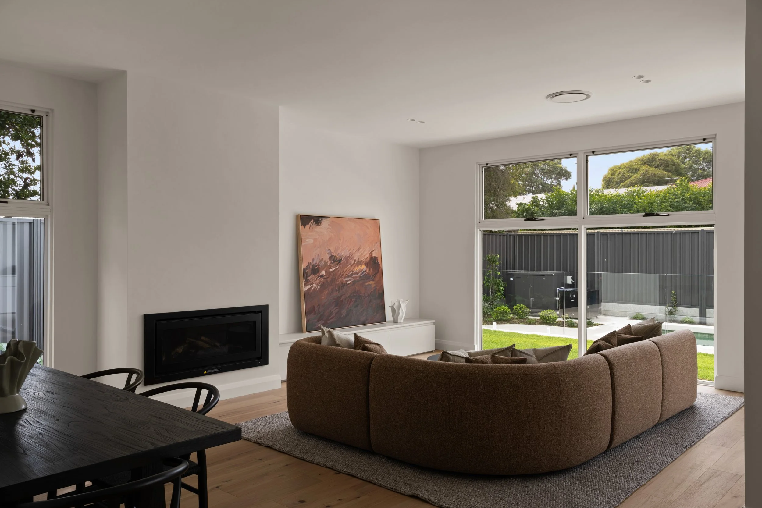 Open-plan living room with a curved sofa and garden outlook in Glenelg North