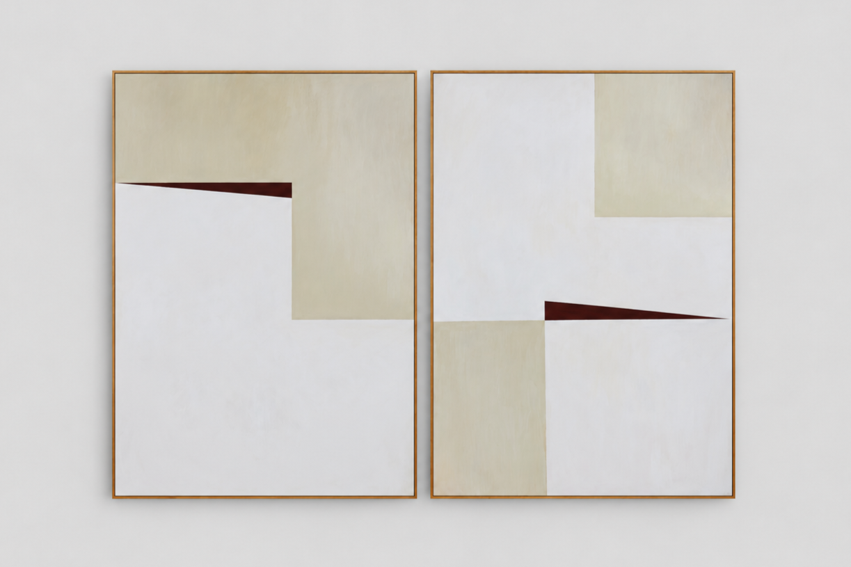 Two abstract, geometric paintings with beige, white, and dark brown triangular shapes, framed in wood, hanging on a white wall.