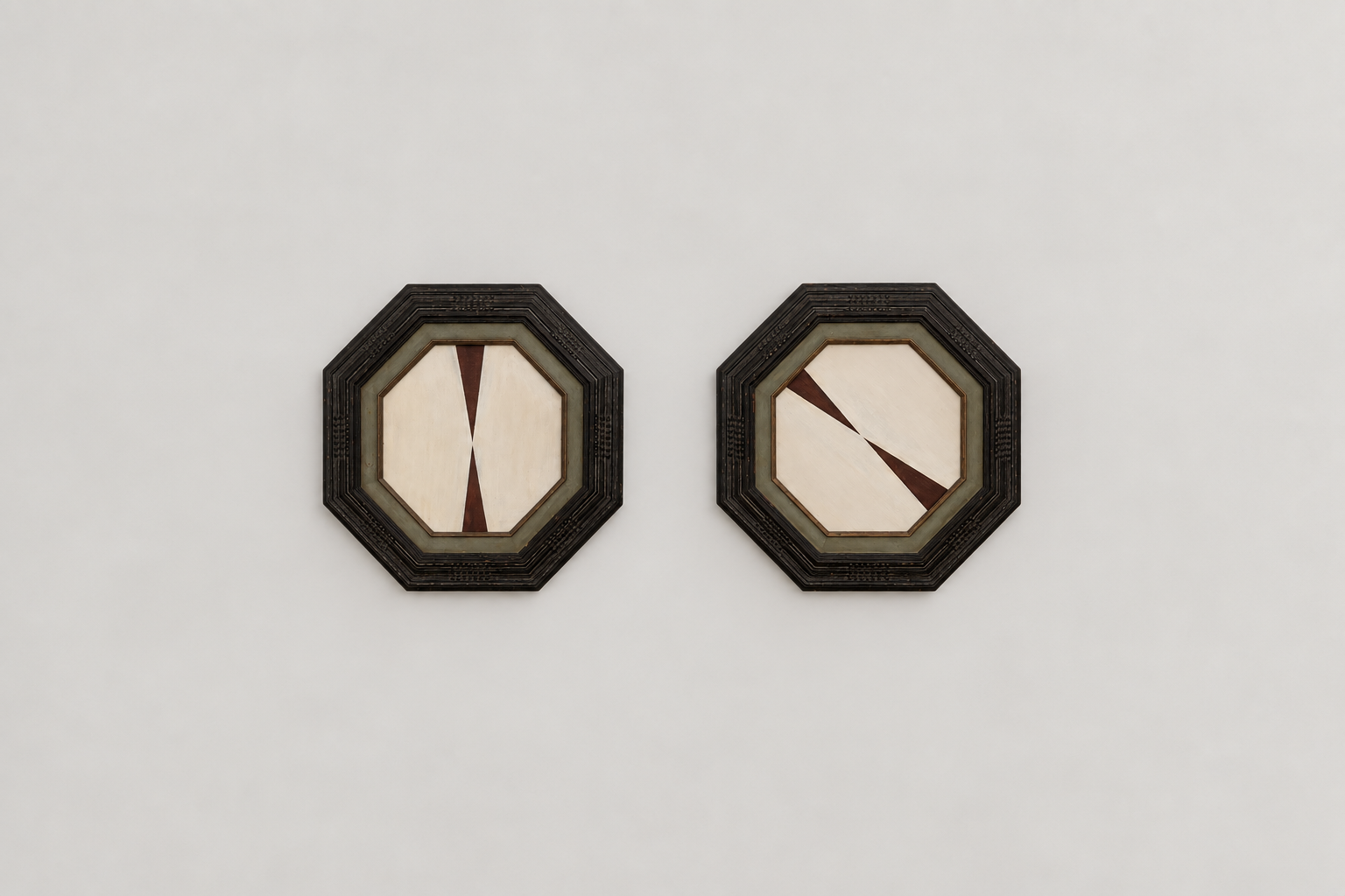 Two octagonal framed artwork pieces with geometric shapes hanging on a plain white wall.