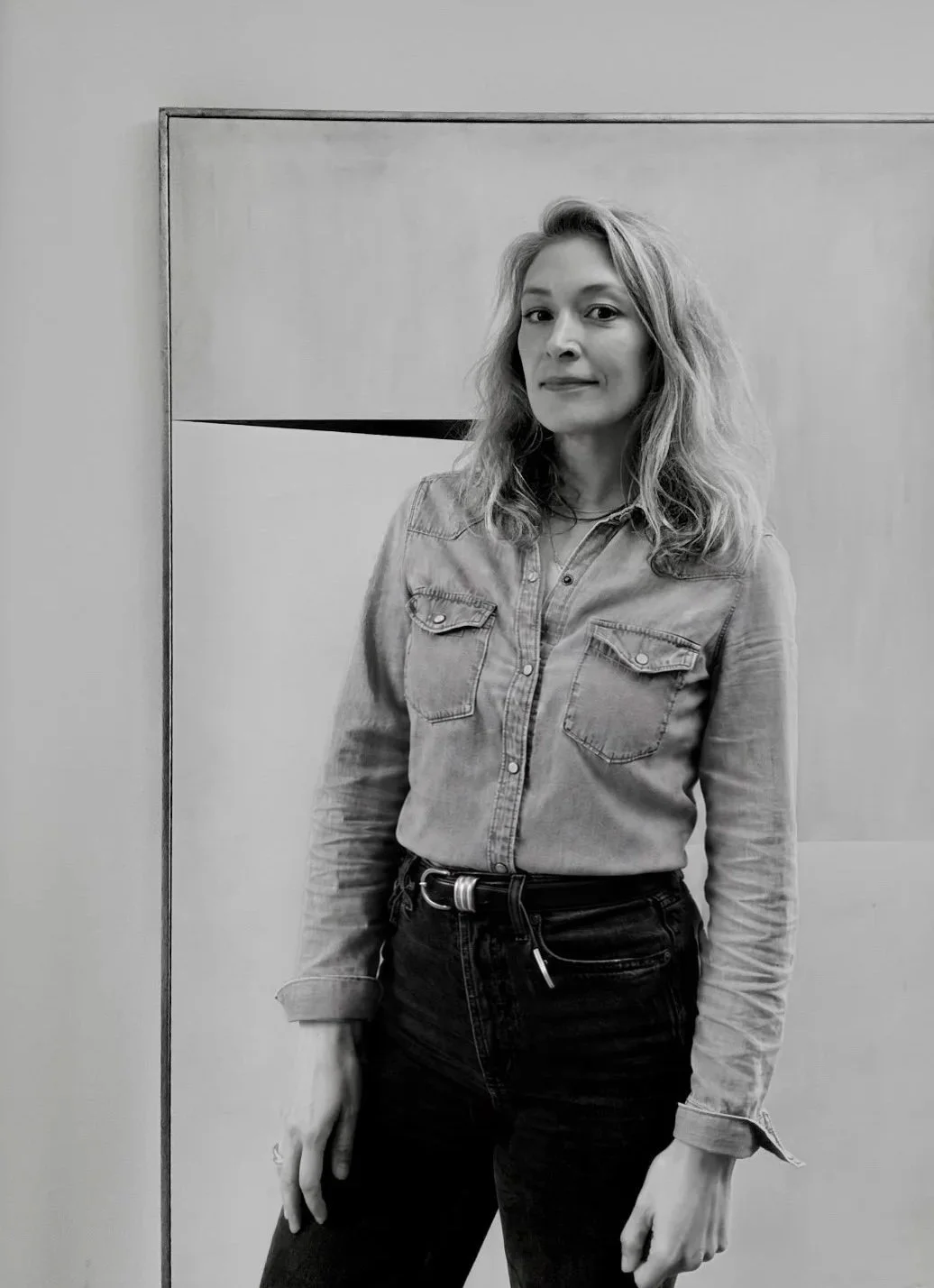 Black and white photo of geometric woman artist Earle stood in front of abstract artwork Precipice