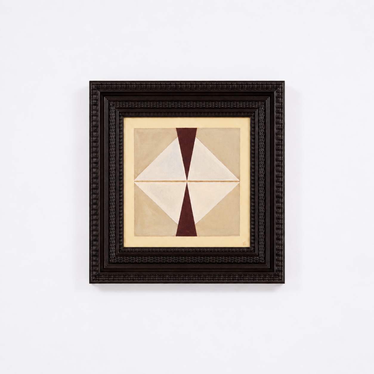 Abstract geometric painting with shades of beige, white, and dark red, framed in a dark, textured frame, hanging on a white wall.