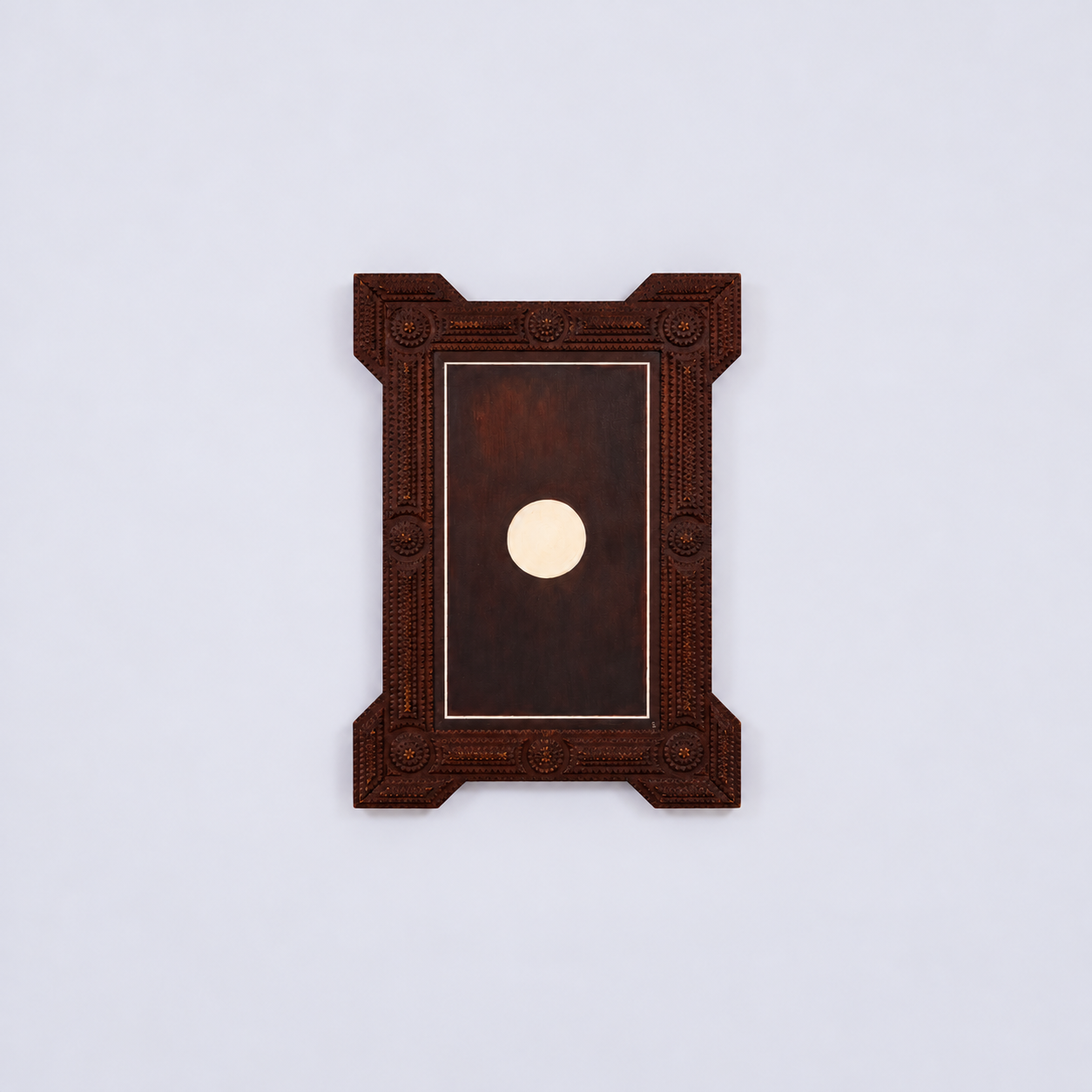 Decorative rectangular mirror with a dark center and a white circle at the bottom, framed by an ornate carved wooden border, mounted on a plain white wall.