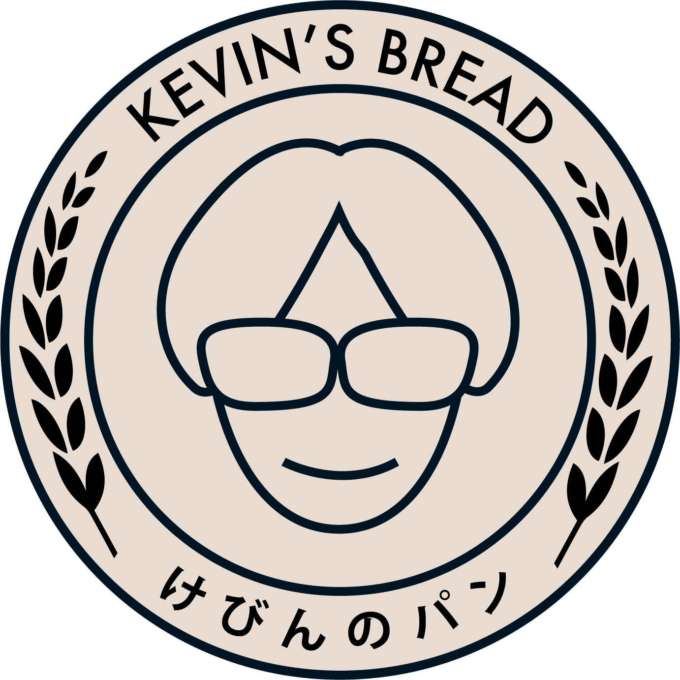 Circular logo for Kevin's Bread featuring a cartoon face with glasses and a smile, Japanese characters at the bottom, and black leaf-like laurel decorations on the sides.
