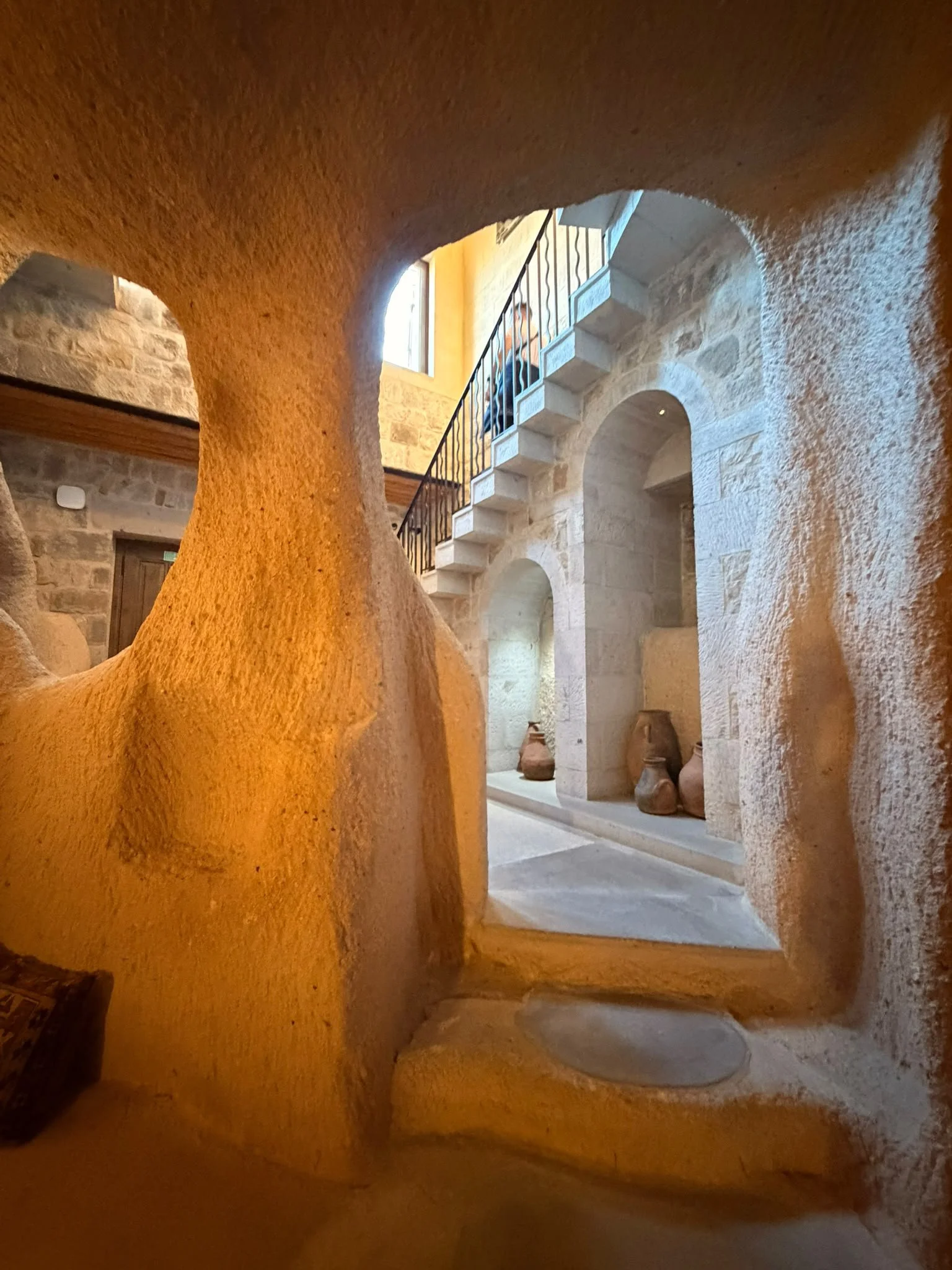 Innenansicht eines historischen Gebäudes mit Steinarbeiten, einer Treppe und Töpferwaren.