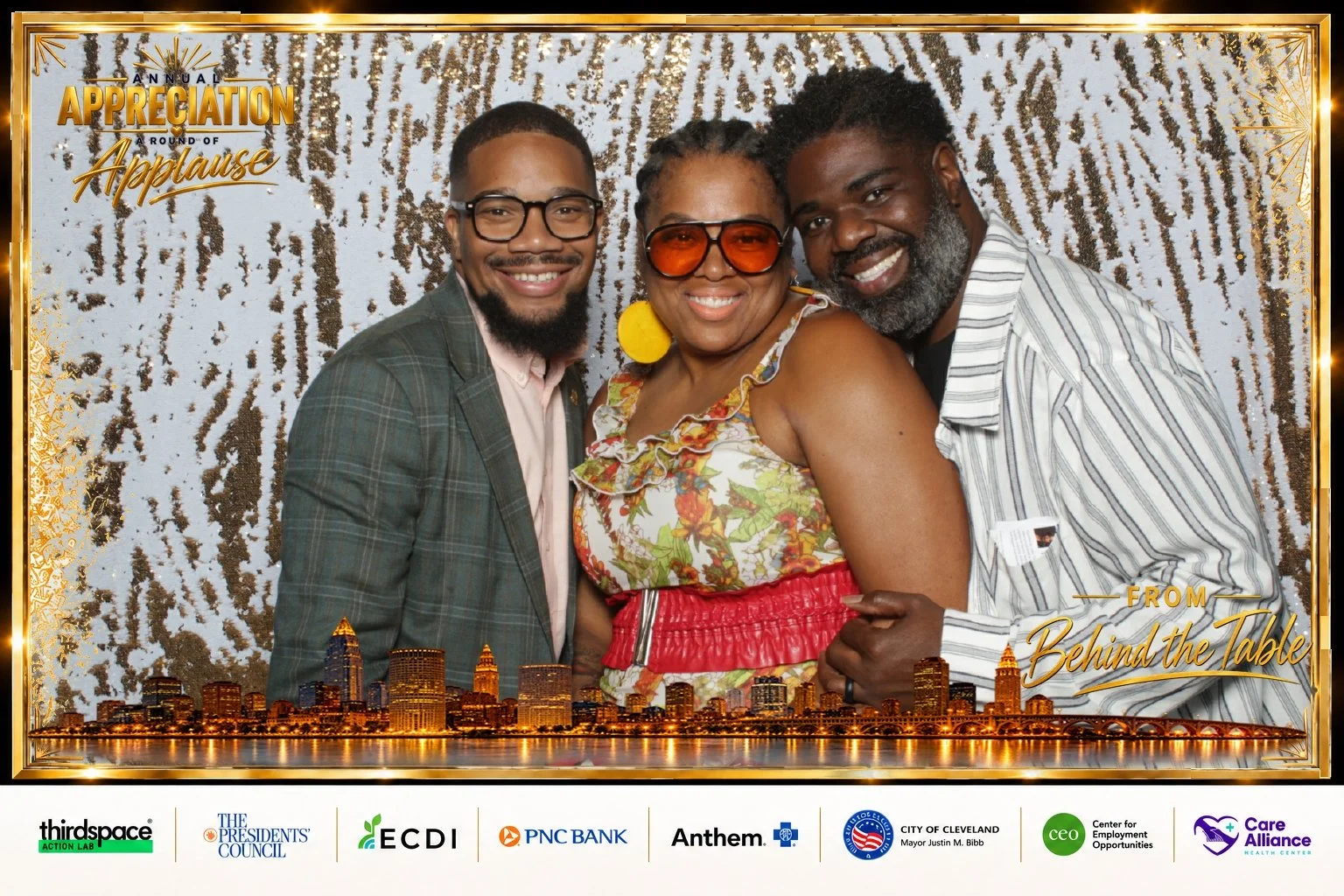 Three smiling Annual Appreciation guests in a gold Cleveland skyline print design with event title and sponsor logos.