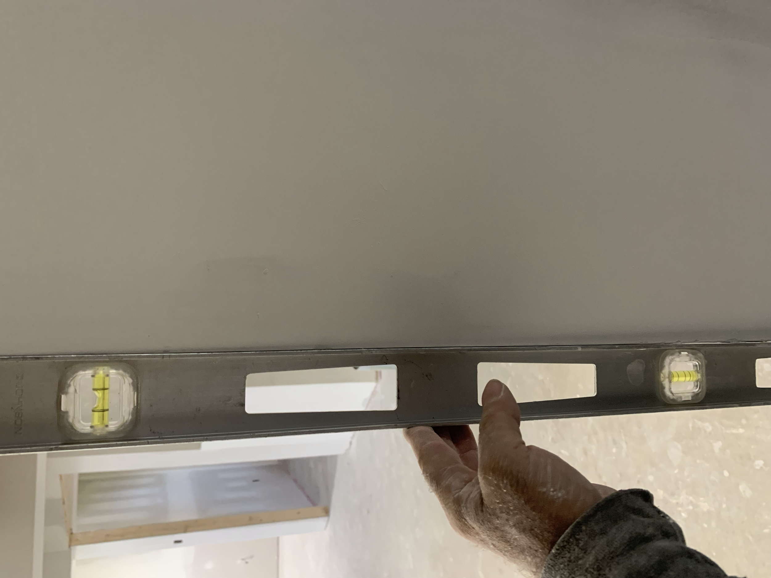 Person holding a level tool against a wall in an indoor construction site