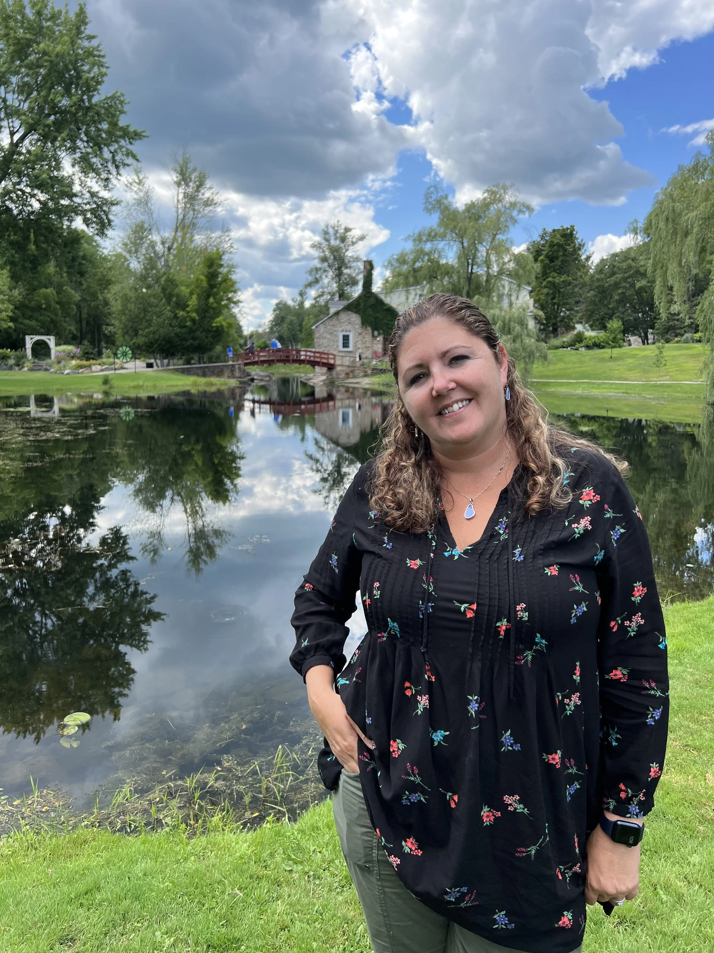 Wendy standing in front of a pond with bridge in the background