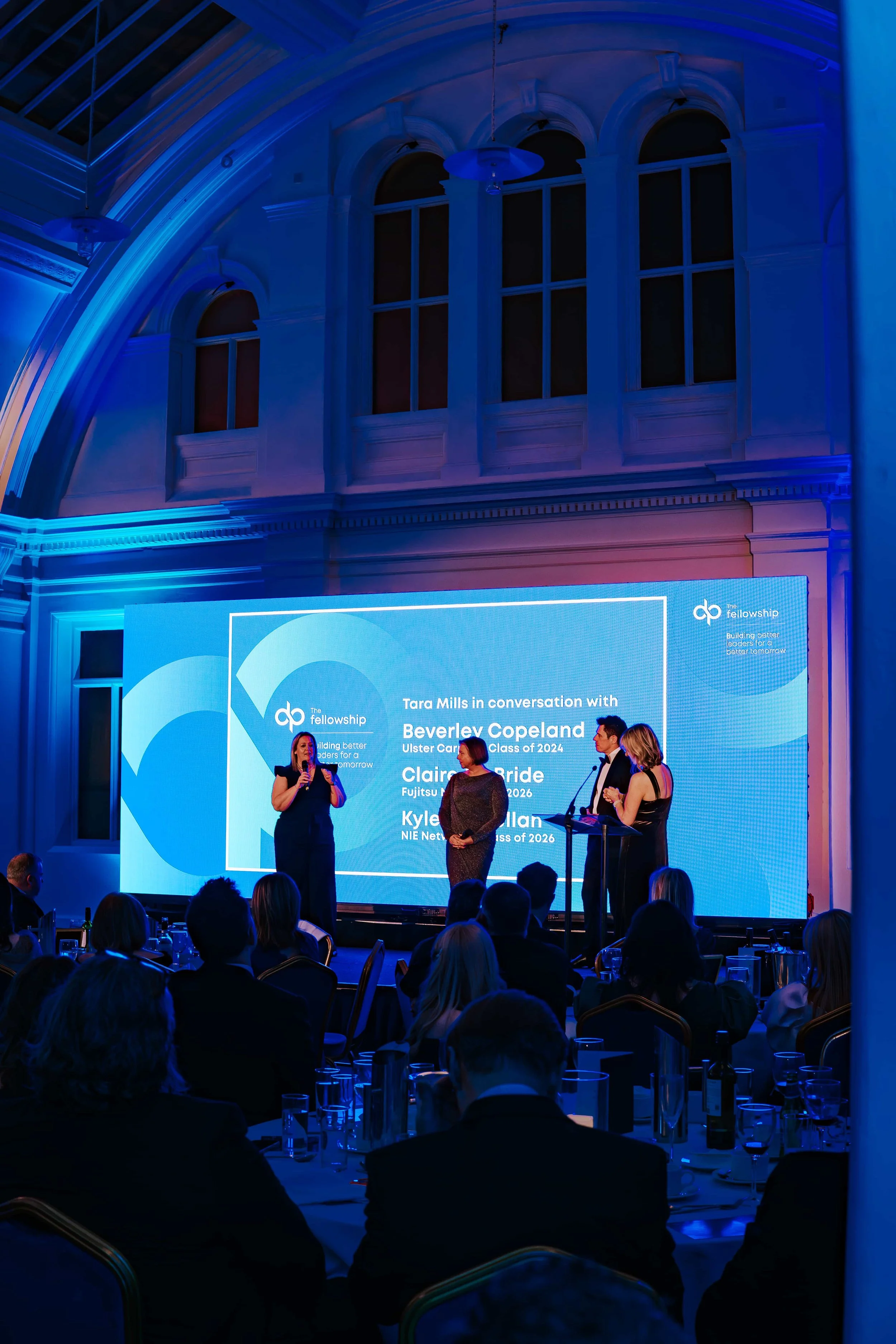 Panel discussion in front of an LED screen at an evening corporate event in a grand hall