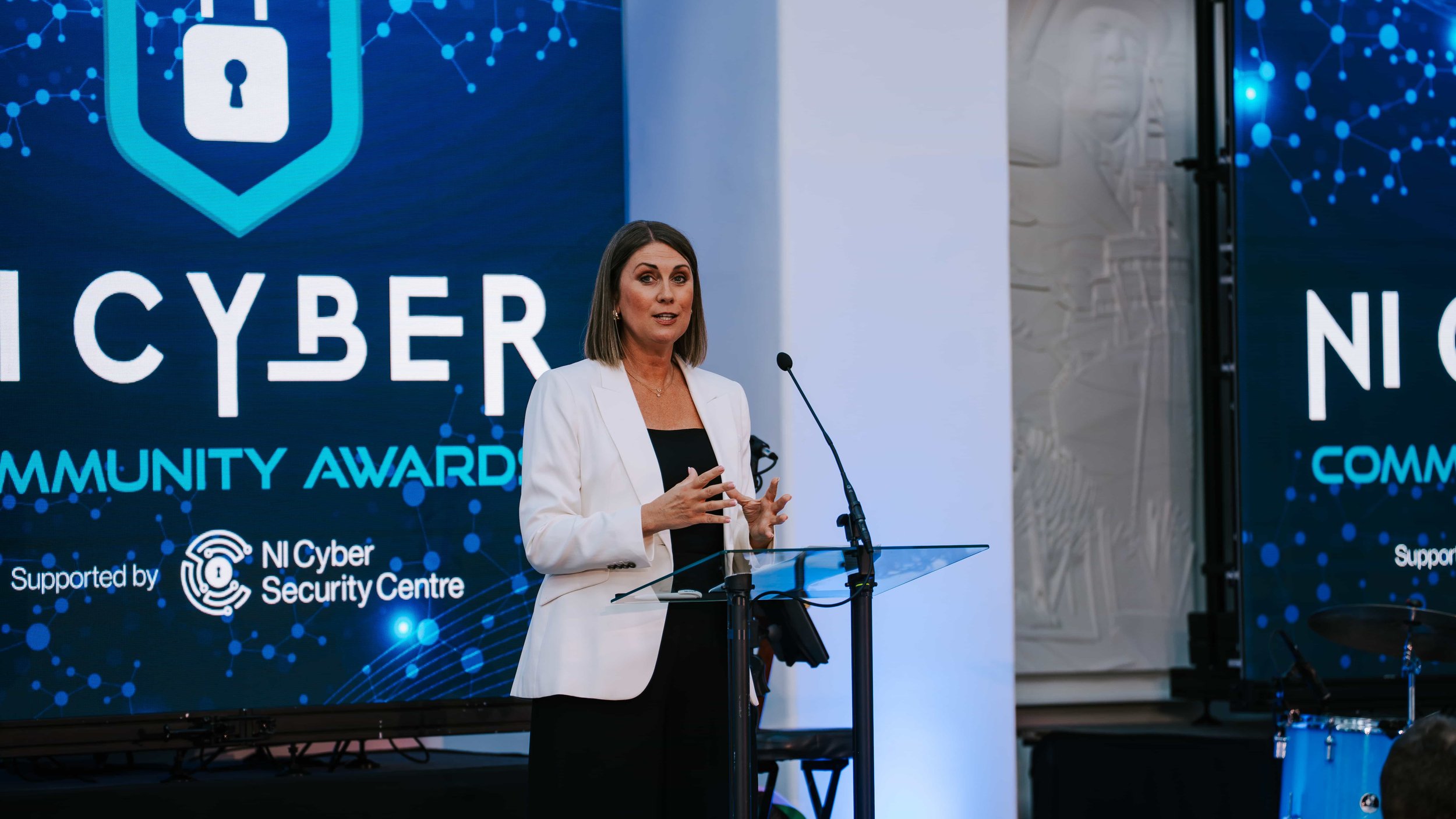 Speaker presenting at an awards ceremony lectern with LED screen backdrop