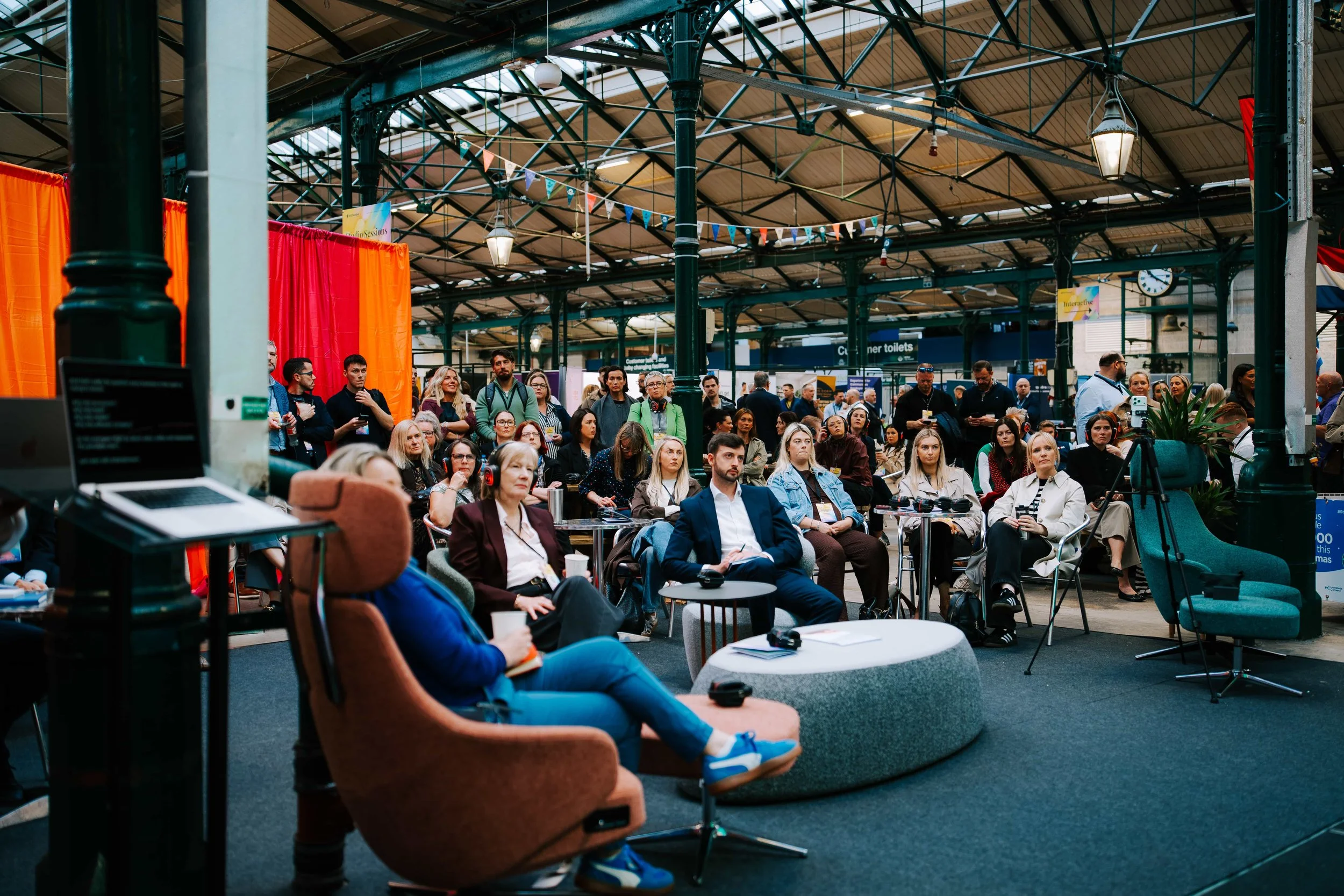 Delegates in silent disco headphones watching a second stage session in the St George's Market hall