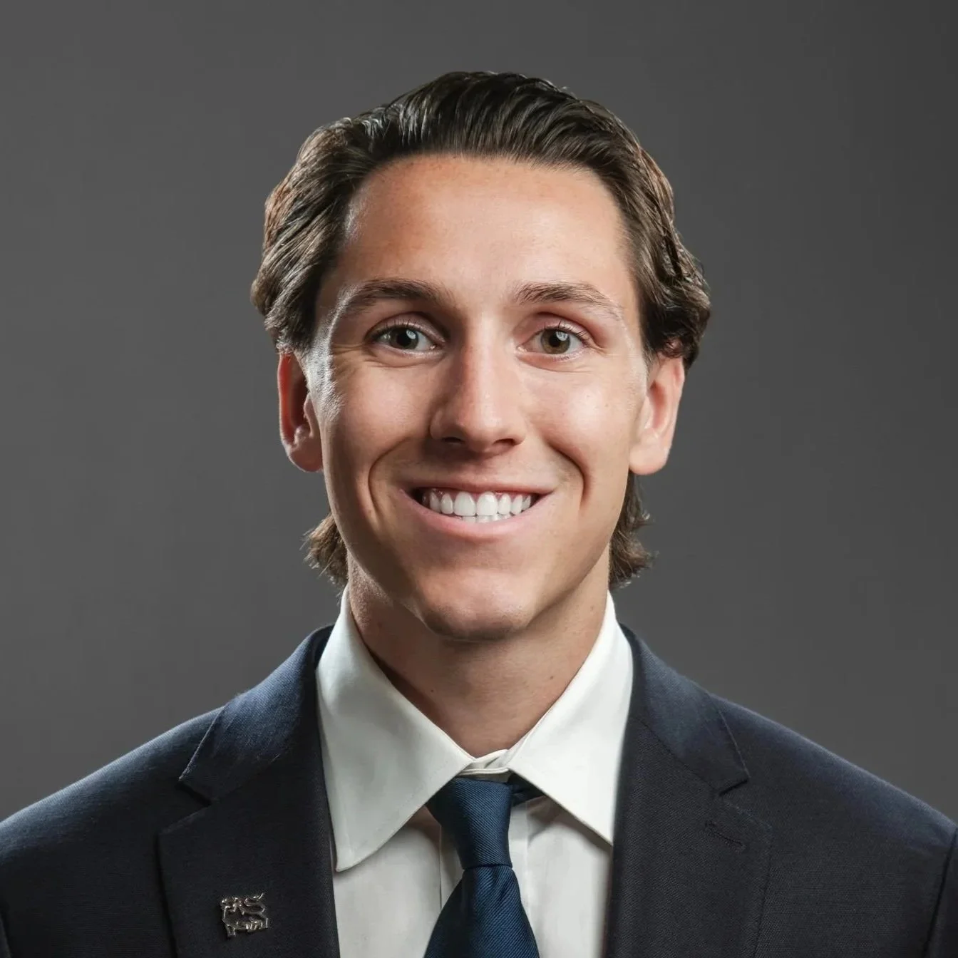 Male finance executive wearing a dark blue suit jacket, white dress shirt and navy blue tie or his headshot session