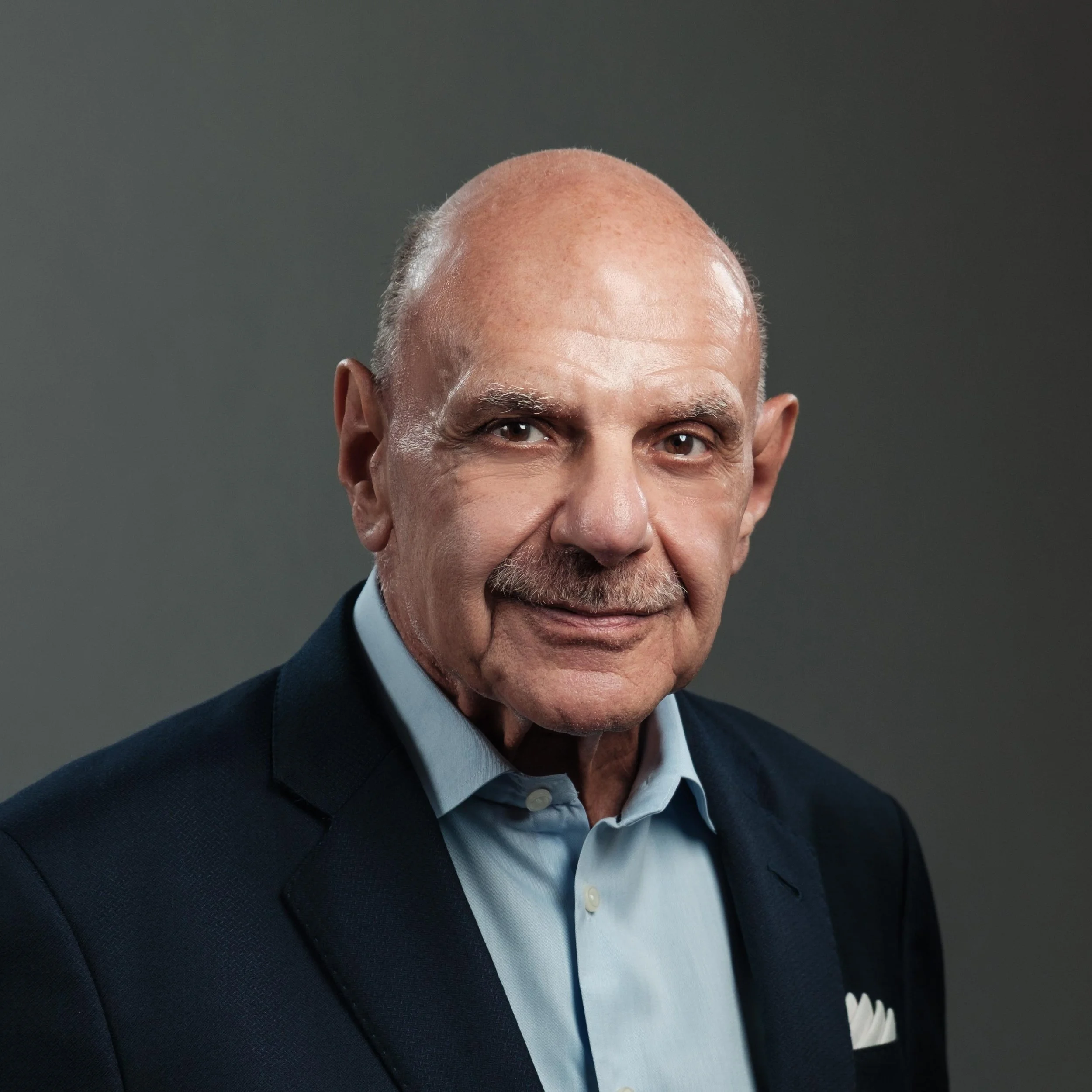Mature Executive Headshot of an older gentleman in his 60s with a dark blue jacket and light blue collared dress shirt