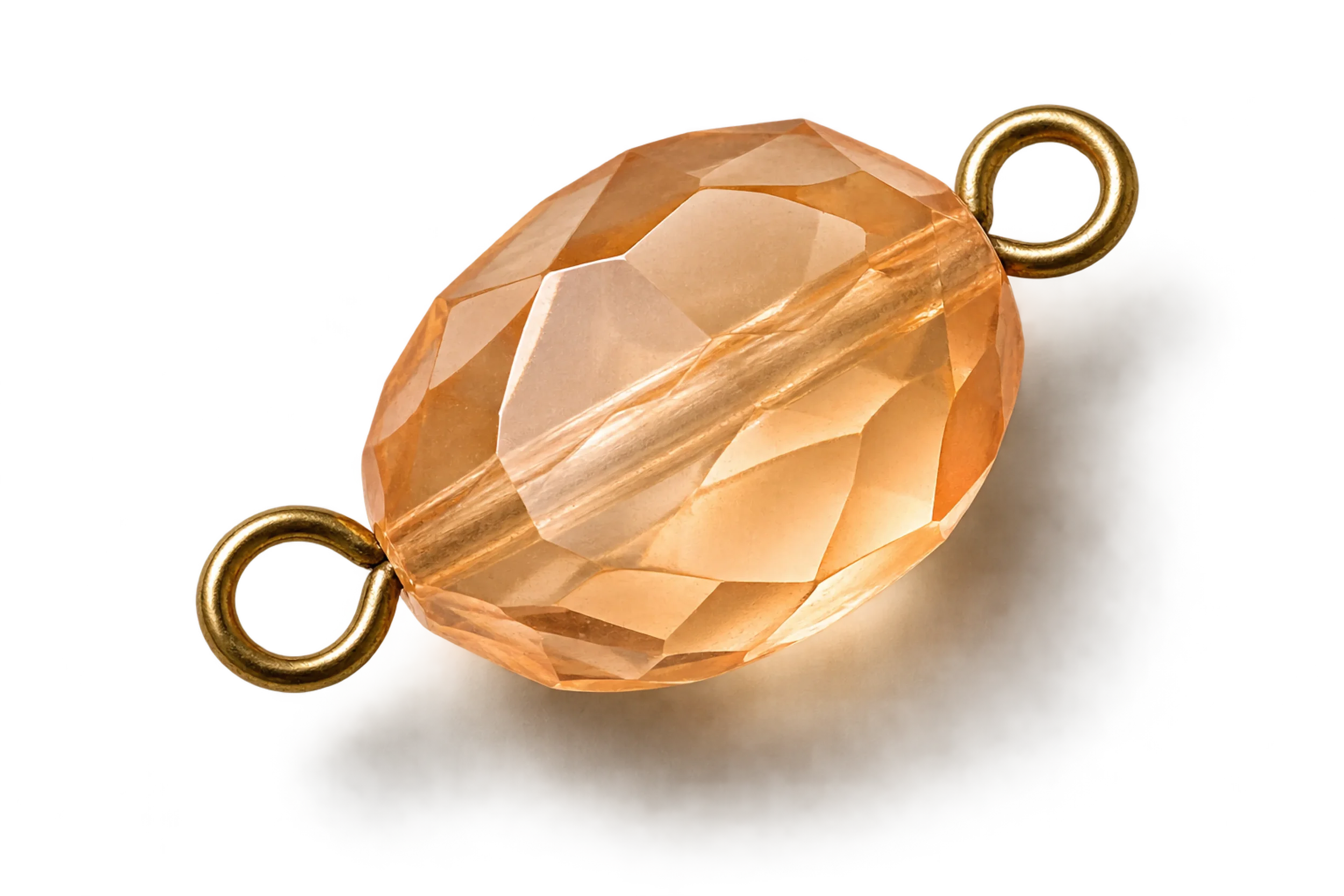 Close-up of a faceted peach-colored gemstone with a gold loop attached, likely a piece of jewelry.