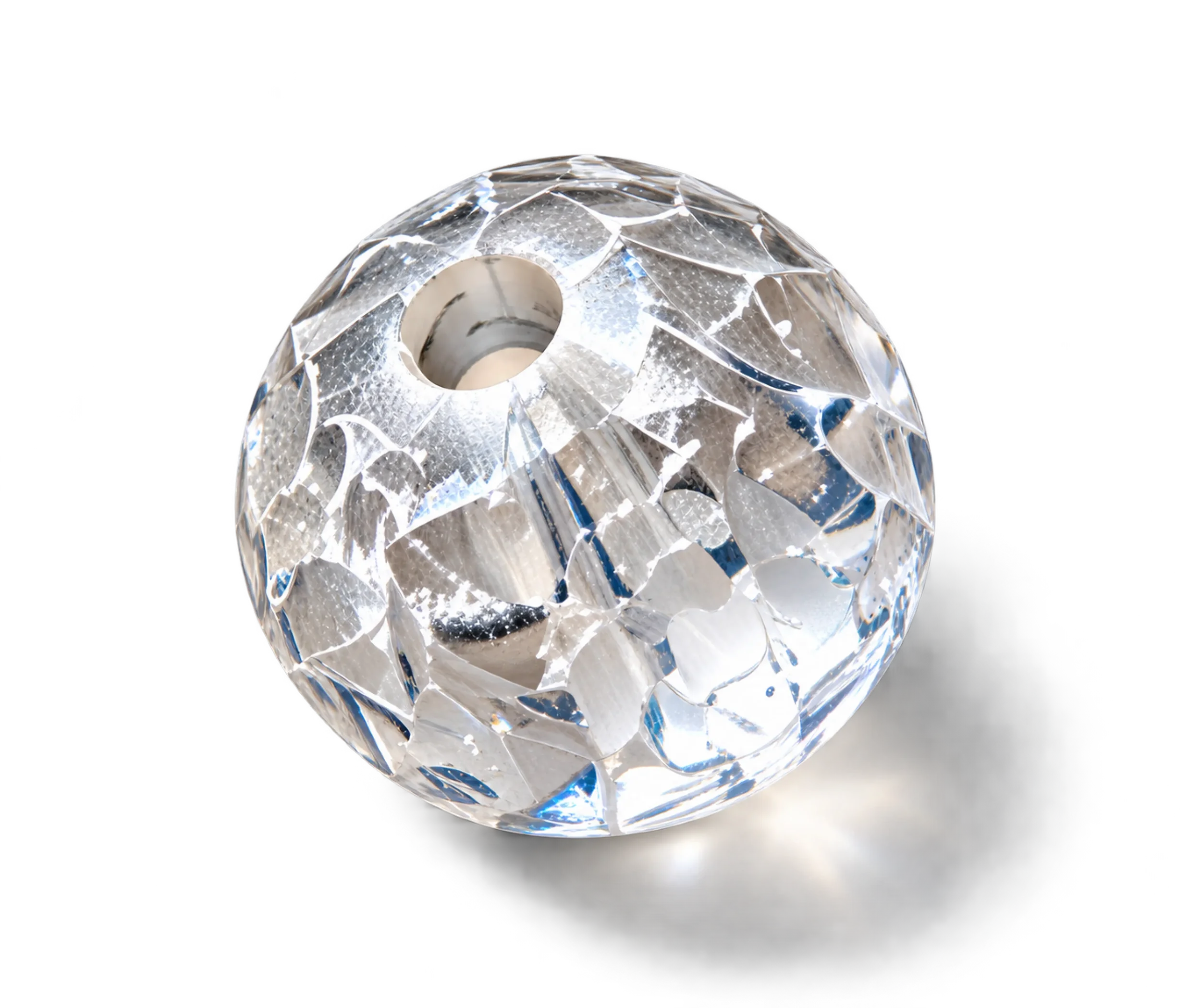 Close-up of a faceted, transparent diamond with a hole in the center, resting on a reflective surface, showcasing intricate cuts and sparkle.