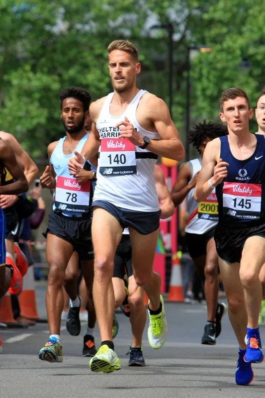 Group of marathon runners competing in a race outdoors on a city street, wearing athletic gear and race bibs.