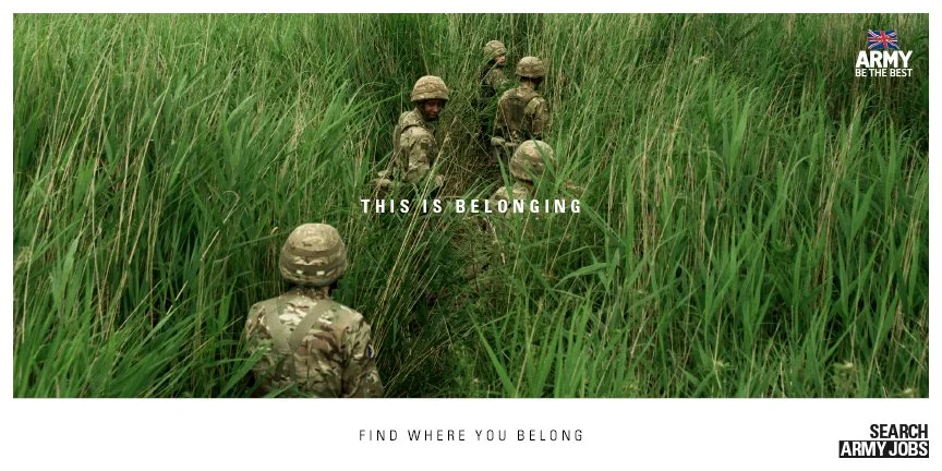 A group of soldiers in camouflage uniforms walking through tall grass in a field.