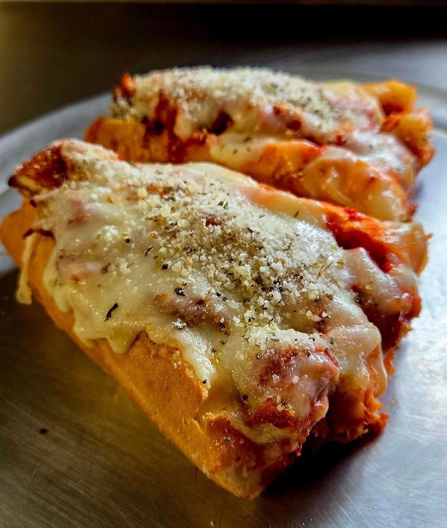 Close-up of a slice of lasagna with melted cheese, tomato sauce, and herbs on top.