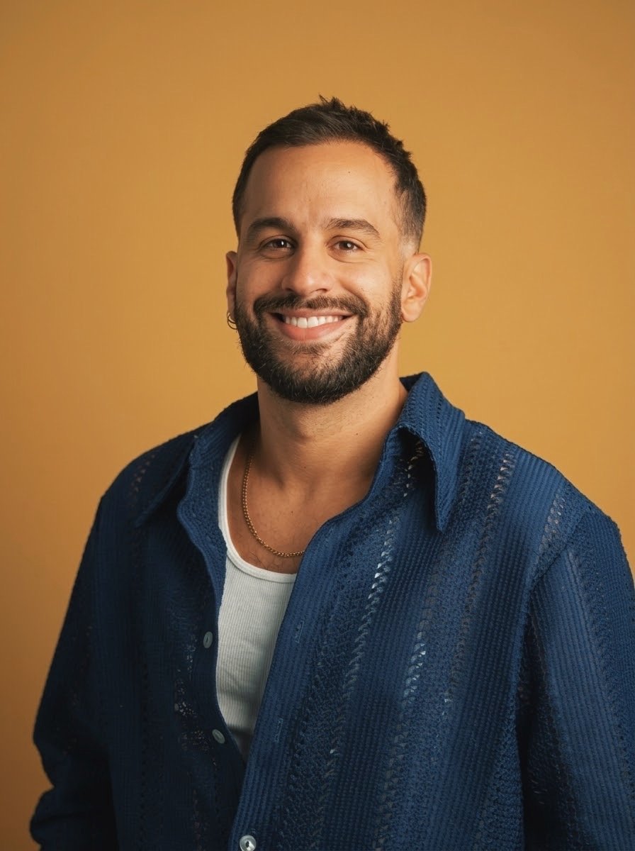 Portrait of Luis Guevara wearing a blue shirt against an orange background.