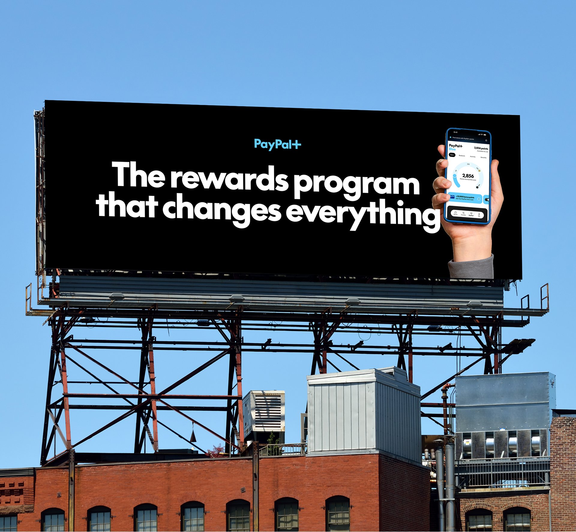 Billboard promoting PayPal+ rewards program on top of a building with HVAC units and metal piping against a clear blue sky.
