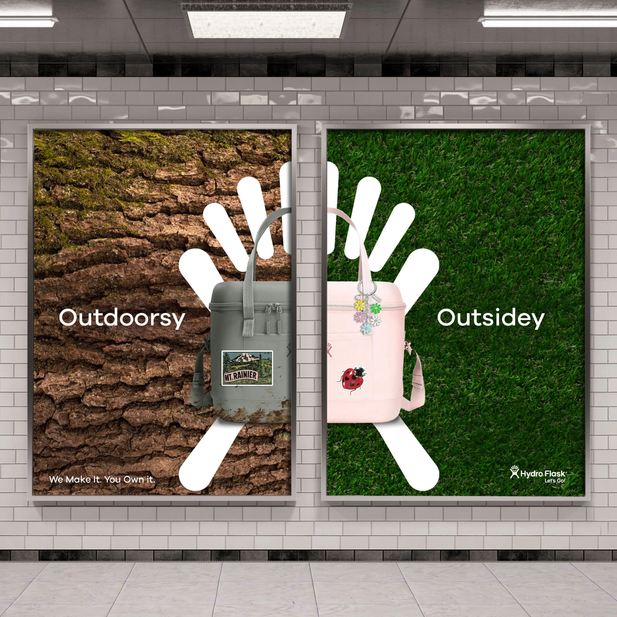 Two posters on a wall side by side. The left poster shows a close-up of a tree trunk with moss and scales with the word 'Outdoorsy' and the slogan 'We Make It. You Own It.' The right poster has a green grass background with the word 'Outsidey' and a small logo at the bottom right corner.