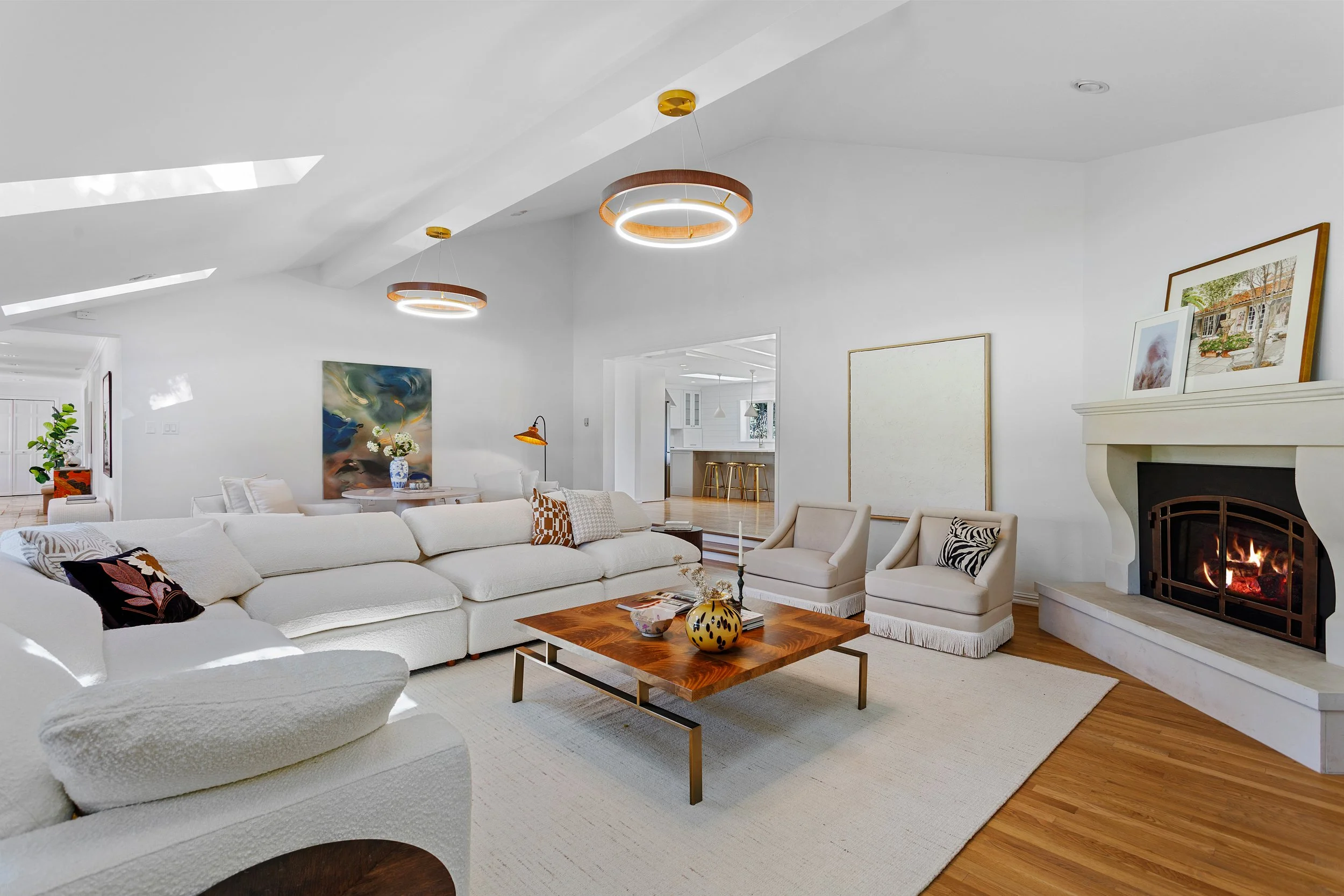 Living room with white couch, armchairs, fireplace, modern circular ceiling lights, and wall art.